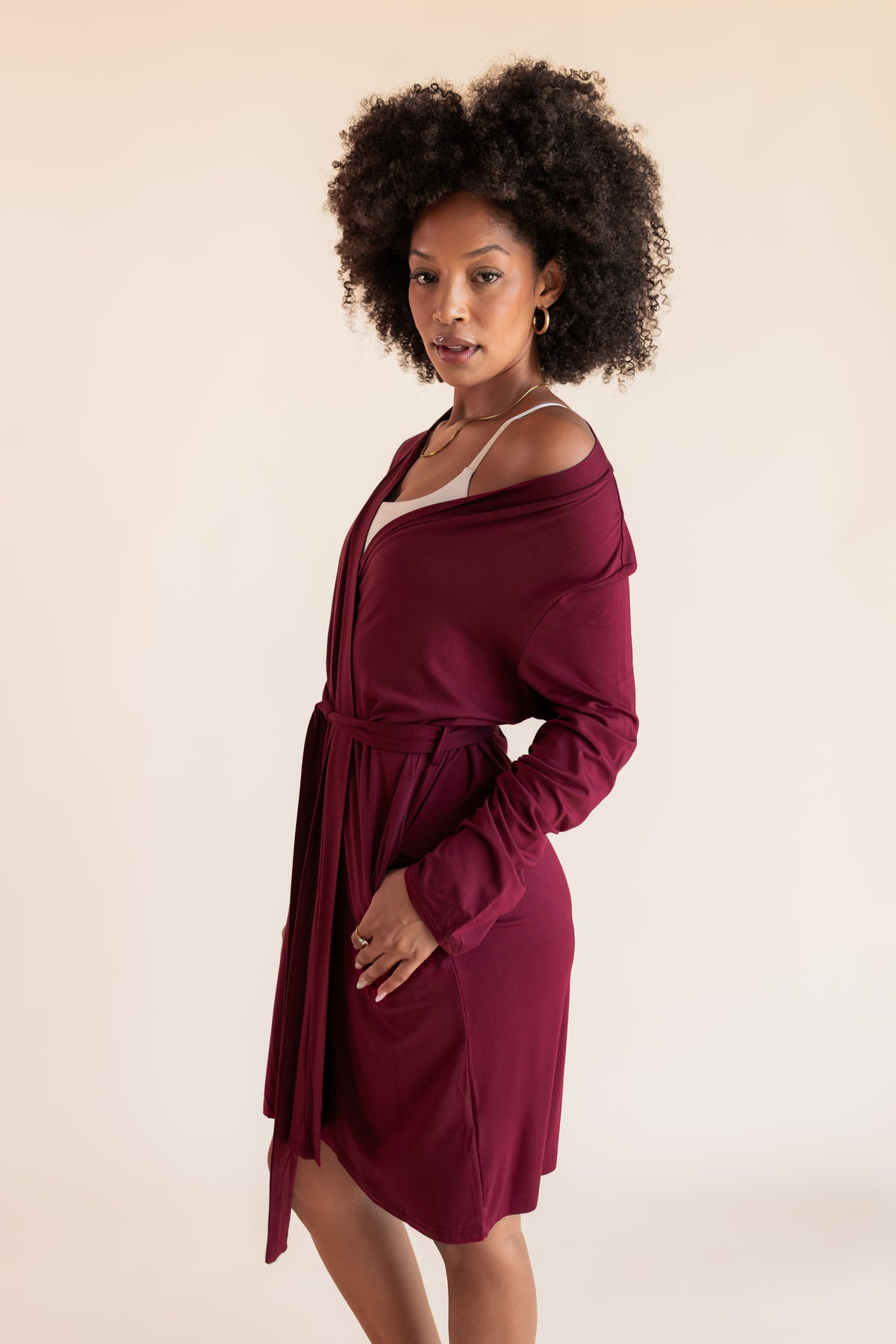 Model posing in back side of Women's Lounge Robe in Burgundy over white bra on a beige background