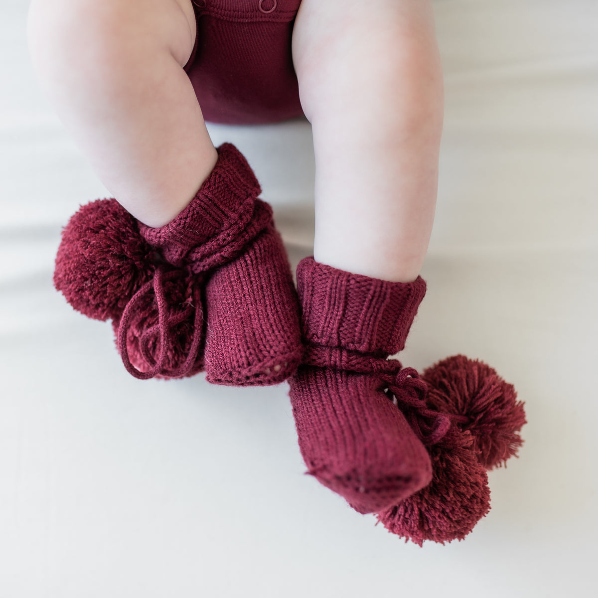 Knit Booties in Burgundy shown on an infant