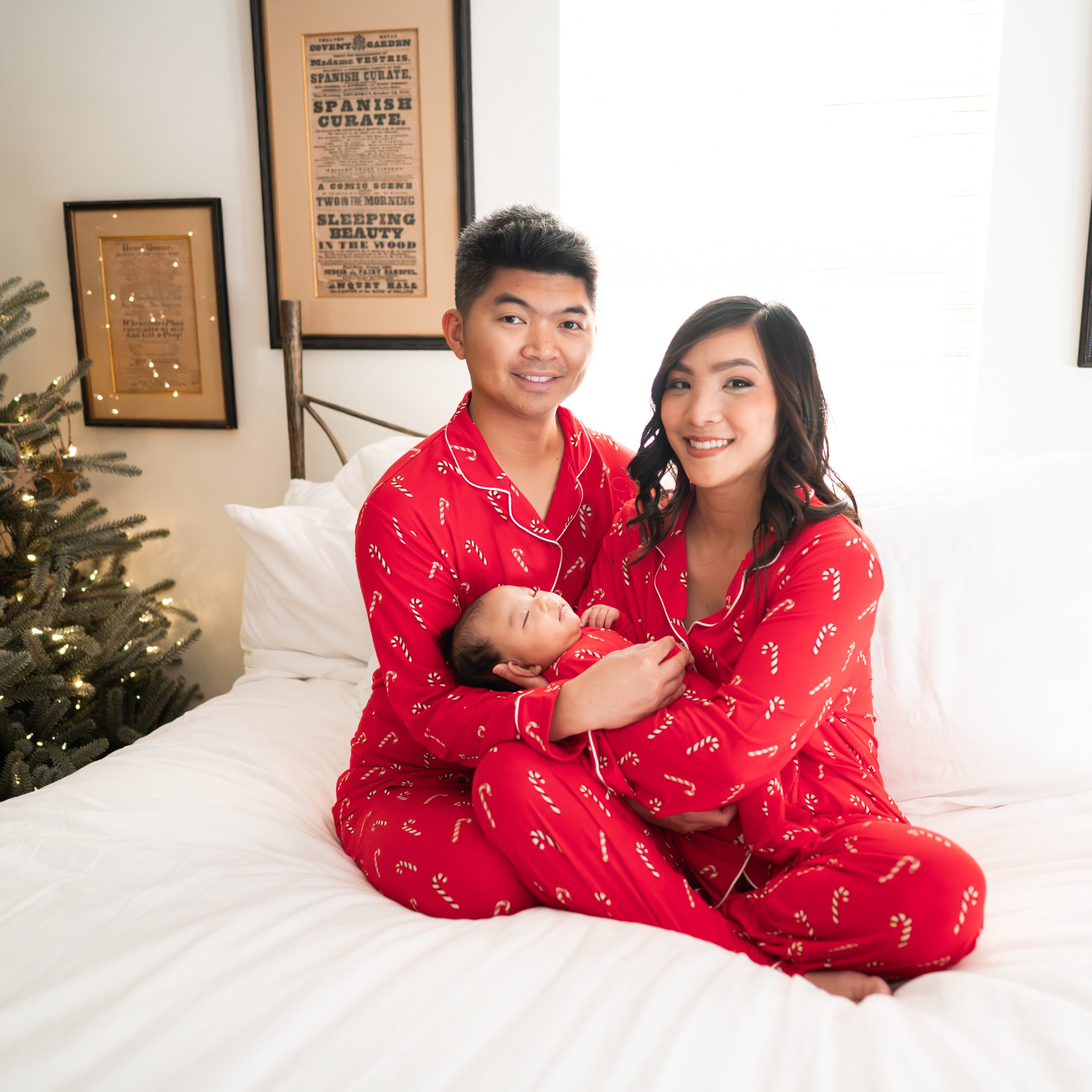 Family of 3 wearing matching red pajamas with candy cane print