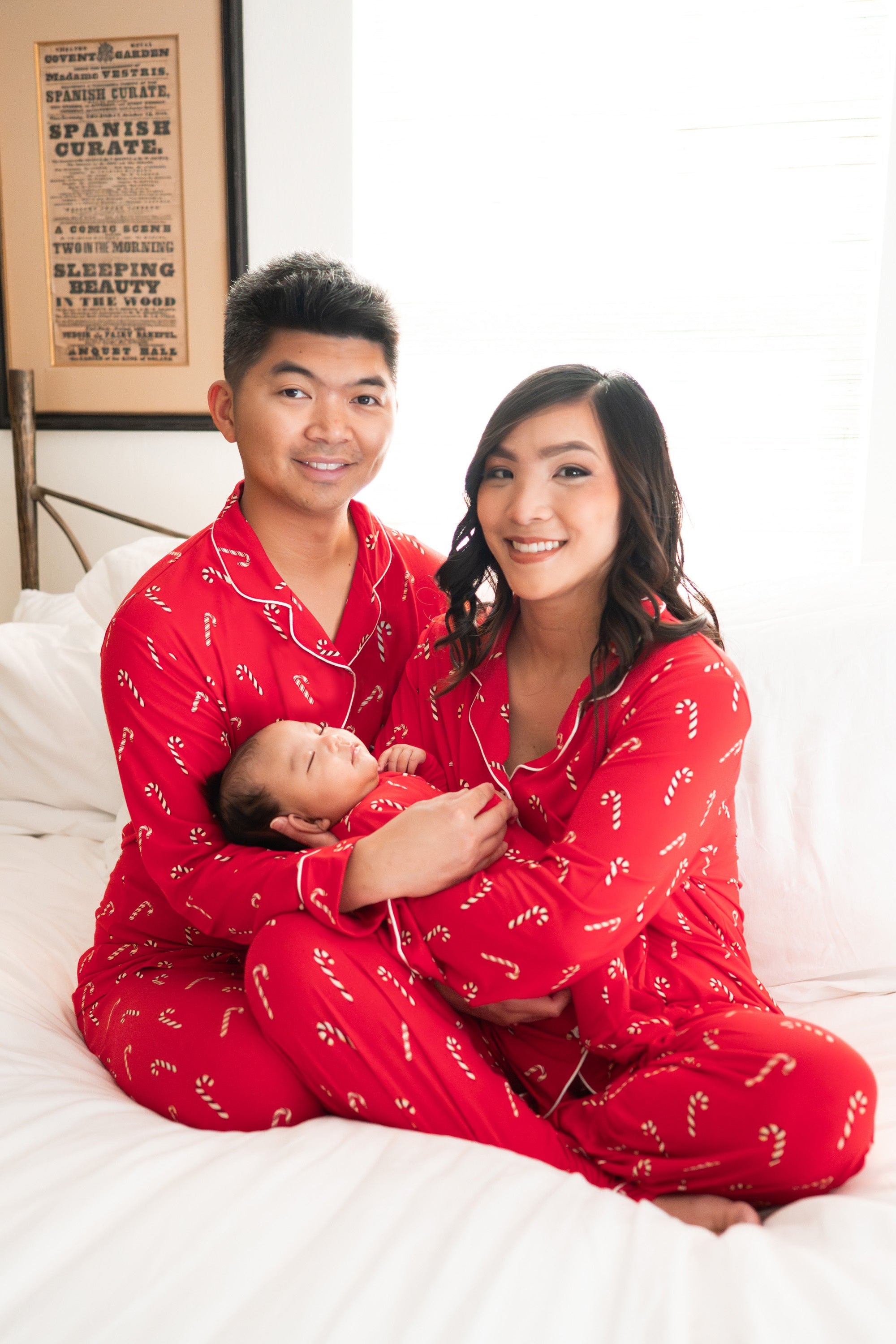 Family wearing matching candy cane pajamas on a white bed