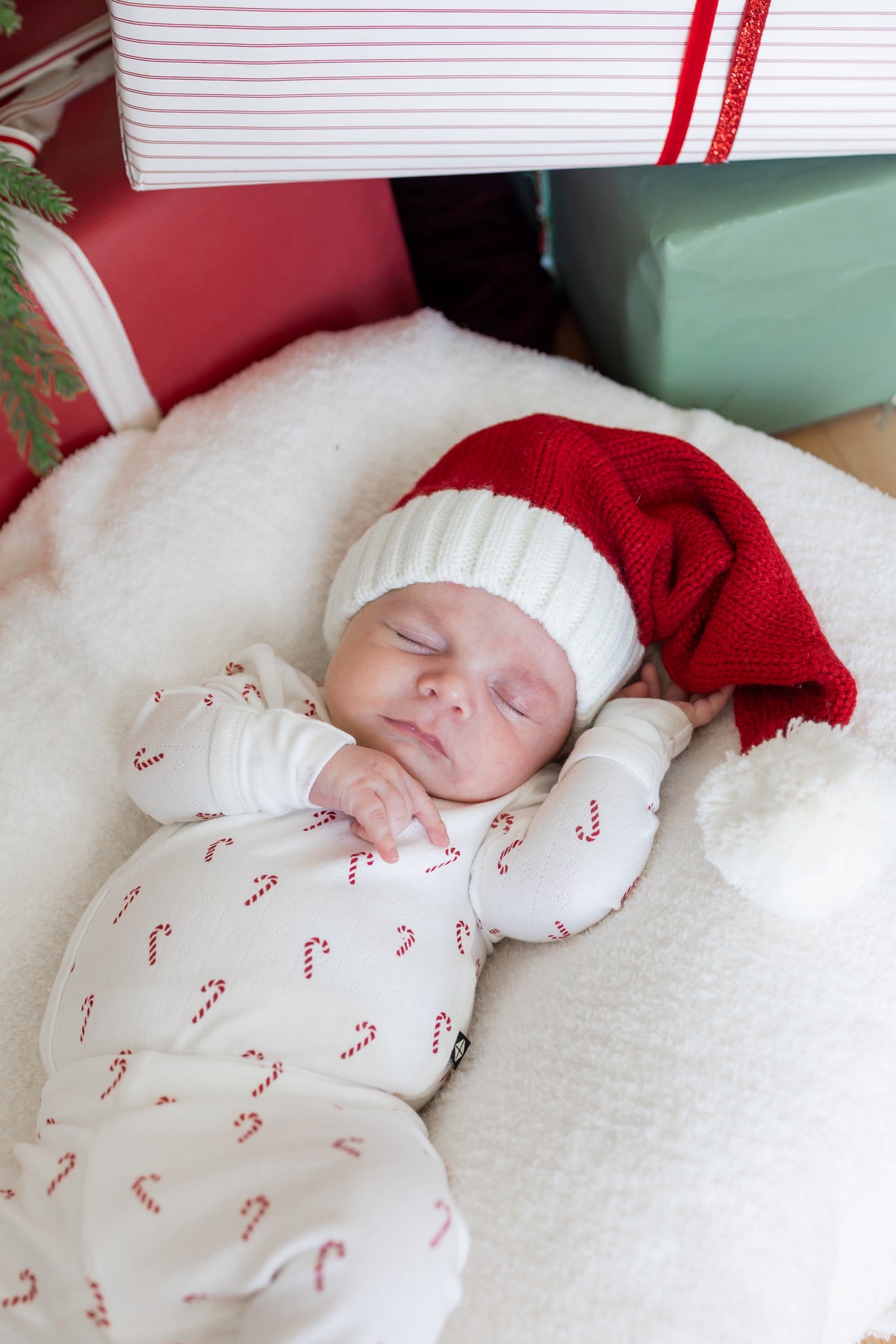 Baby sleeping wearing Pointelle Kimono Set in Candy Cane and red hat on a white sheet