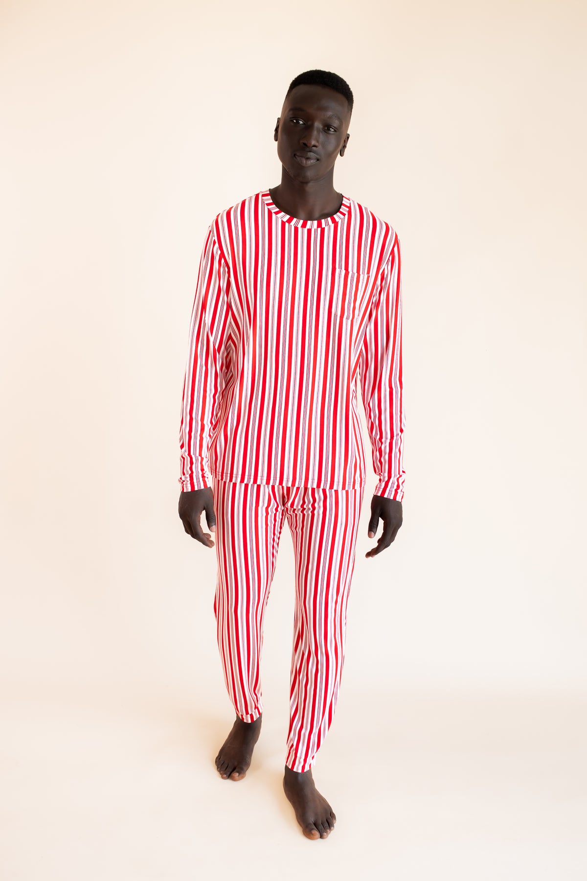 Modal wearing Men's Jogger Set in red and white Peppermint Stripes print on a beige background
