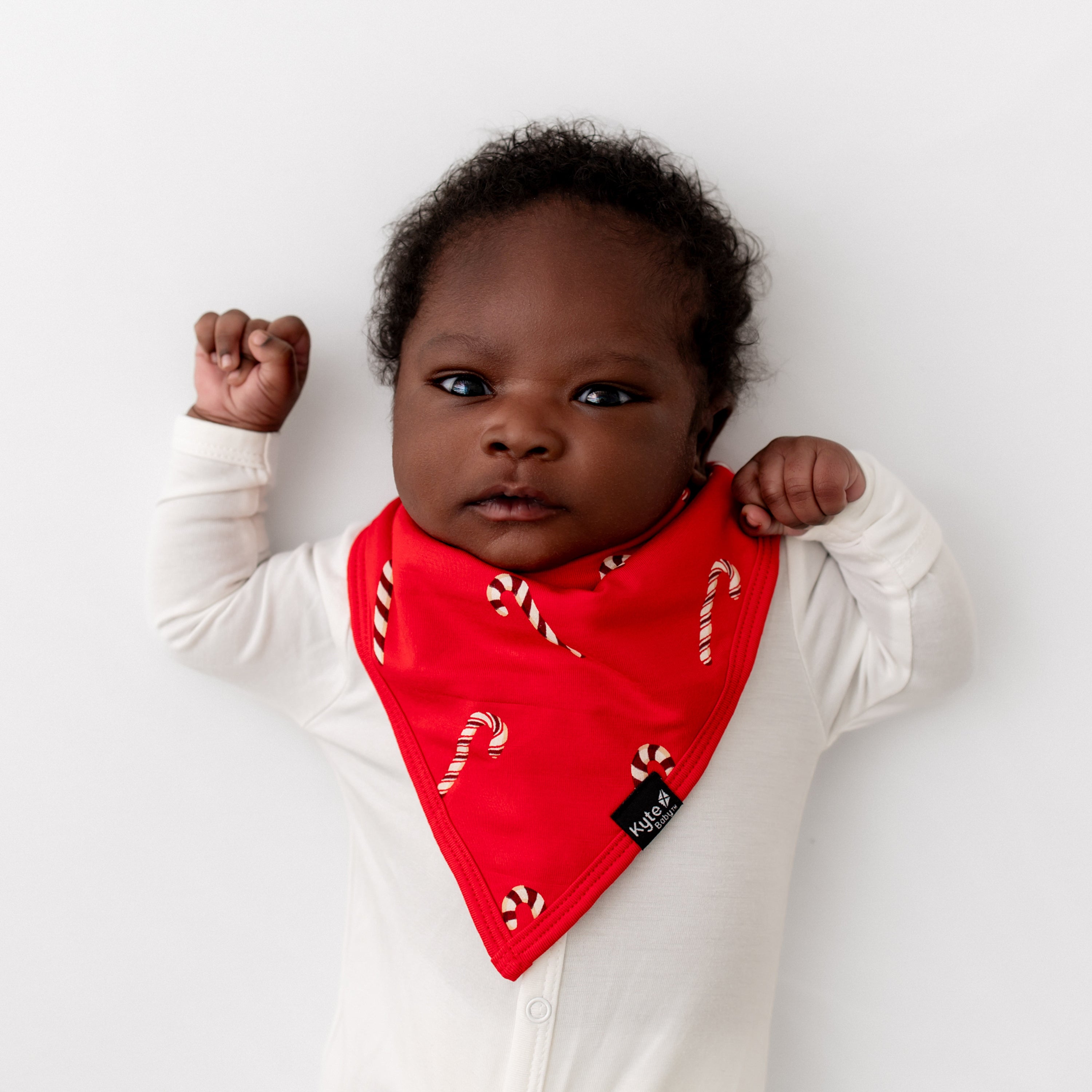 Newborn baby laying down wearing the Bib in Candy Cane