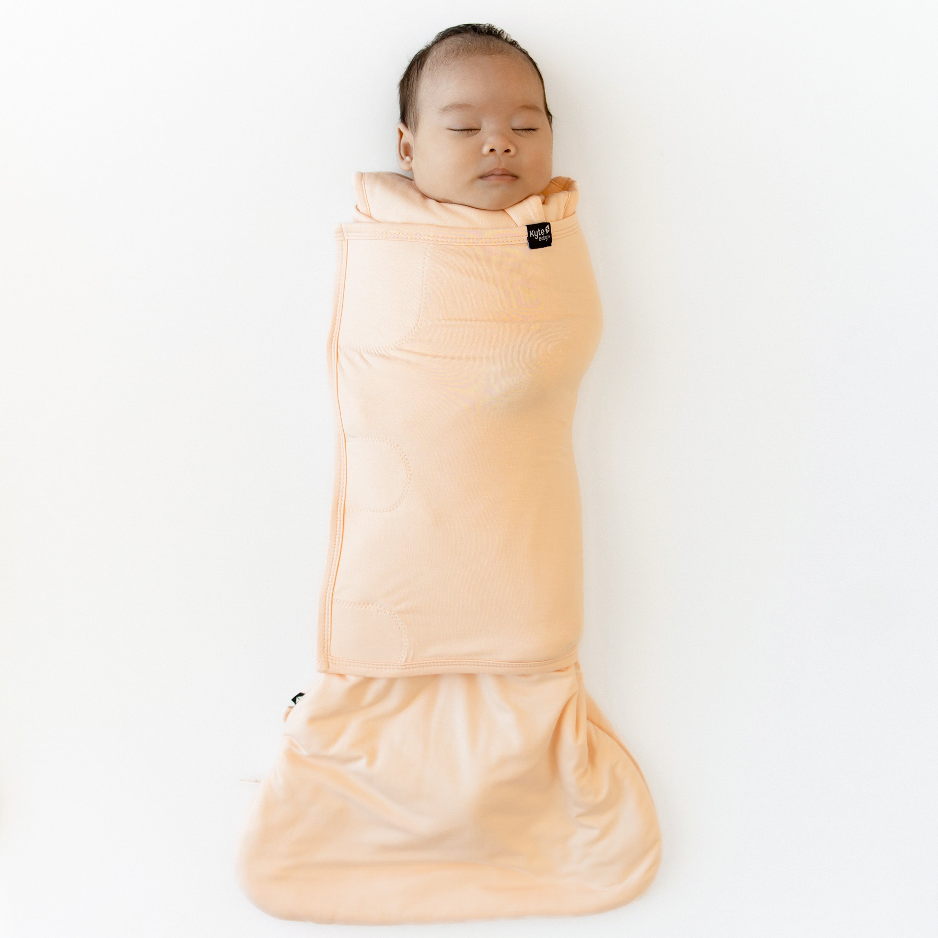 Sleeping infant shown swaddled in the Sleep Bag Swaddler in Canyon 1.0