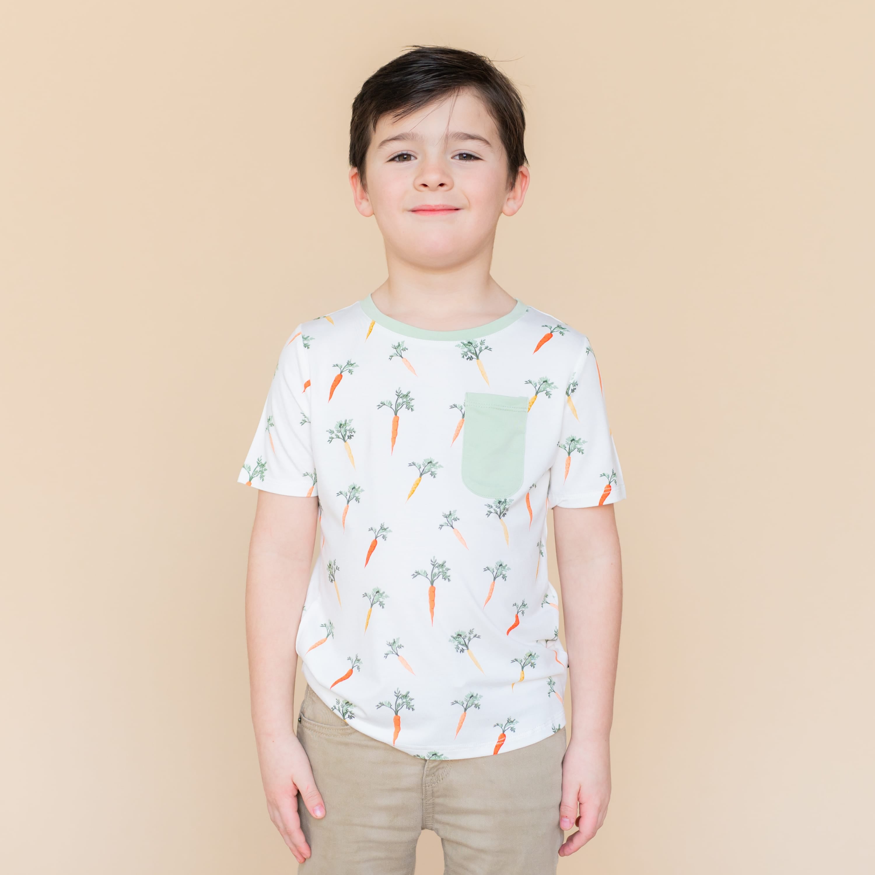 Smiling boy wearing the Toddler Crew Neck Tee in Carrot with khaki colored pants