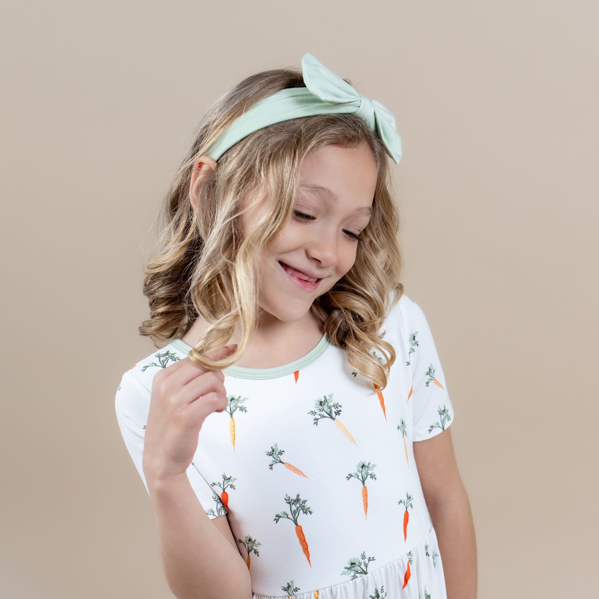 Close up of smiling model wearing the Twirl Dress in Carrot with light green bow