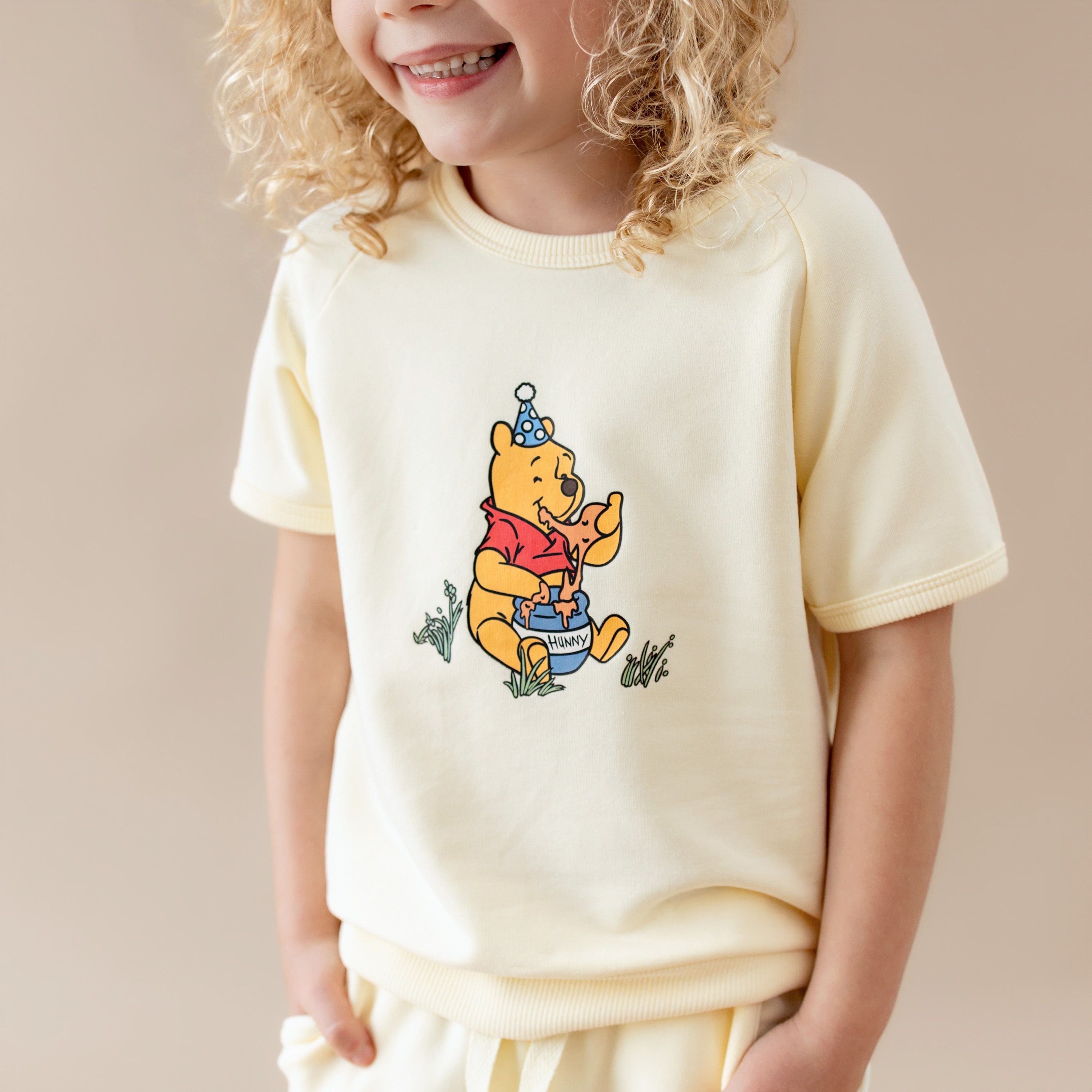 Close up of the winnie the pooh character in the center of the shirt of the Short Sleeve Jogger Set in Winnie the Pooh on Chamomile