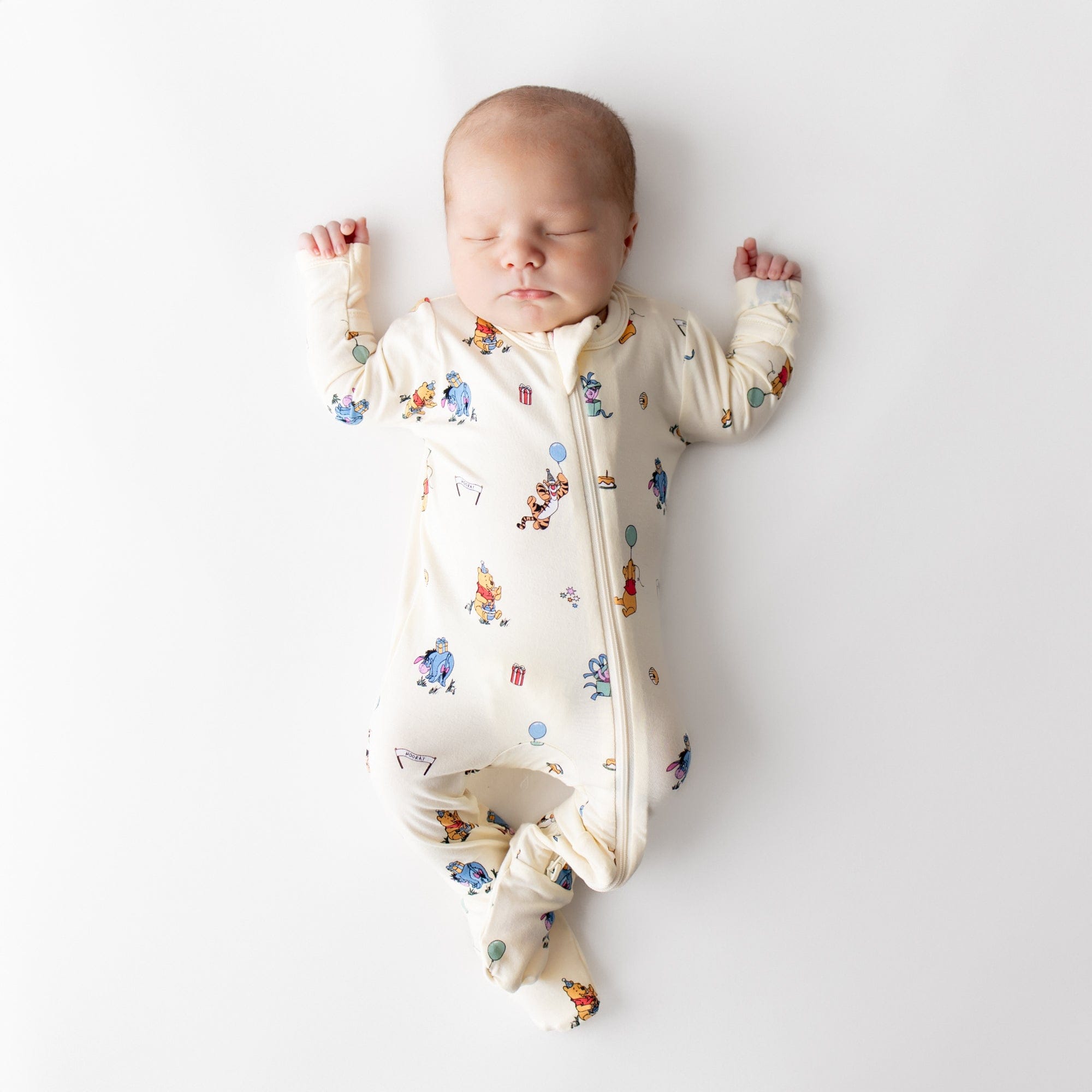 Sleeping newborn wearing the Zippered Footie in Winnie the Pooh Celebration