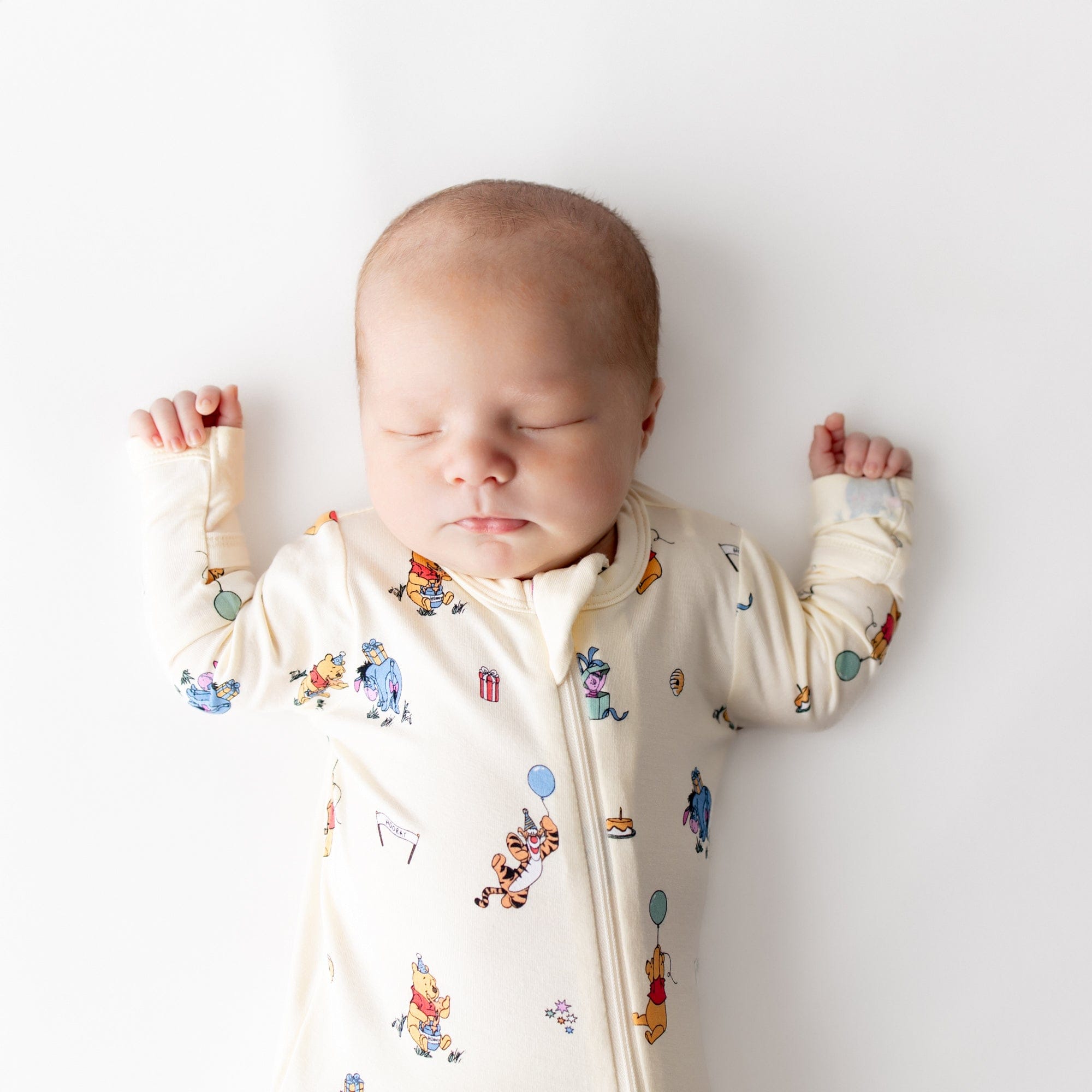 Close up of sleeping newborn wearing the Zippered Footie in Winnie the Pooh Celebration