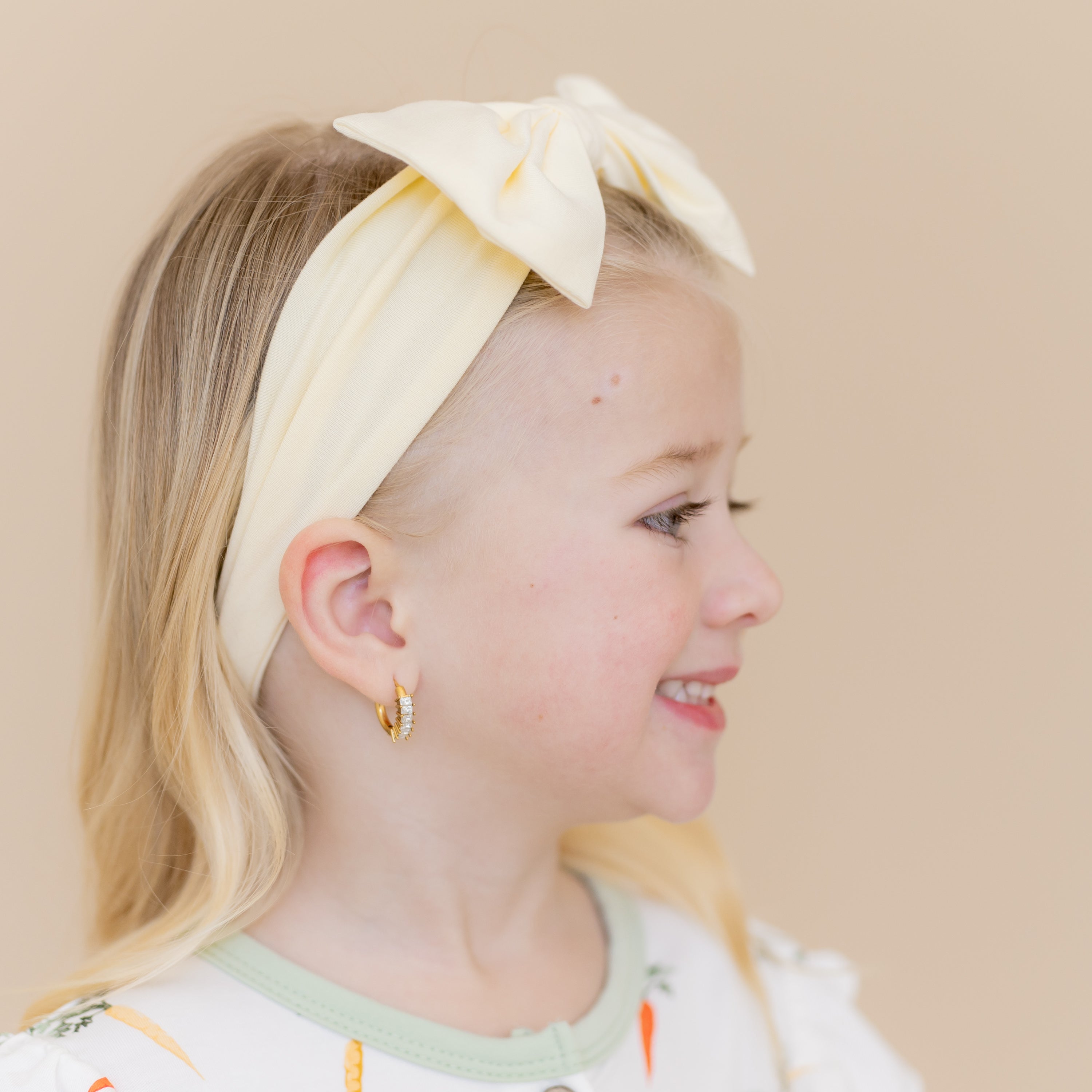 Side view of the Bow Headband in Chamomile shown on a young girl
