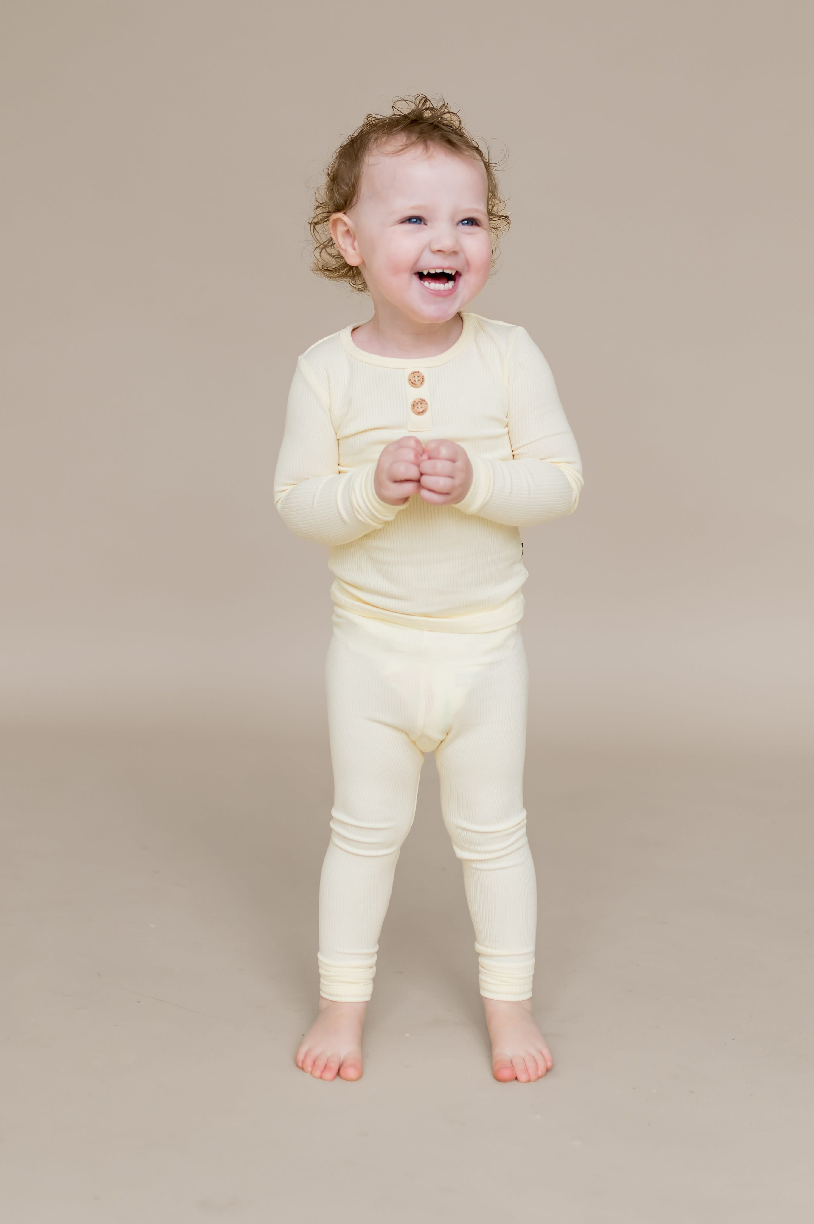Smiling child standing wearing the Ribbed Henley Set in Chamomile