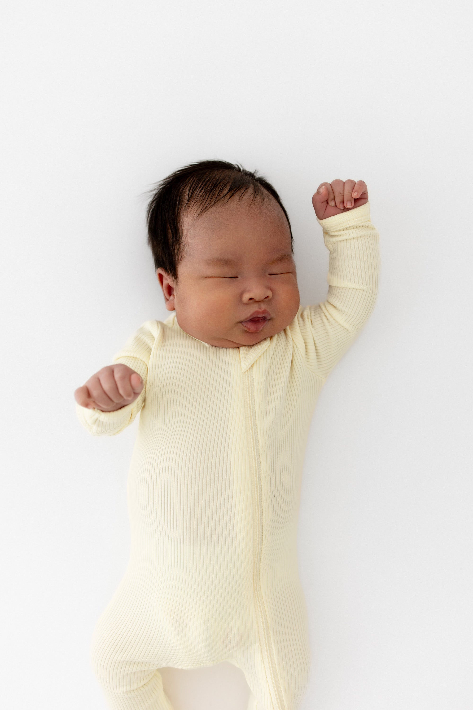 Newborn stretching wearing the Ribbed Zipper Footie in Chamomile