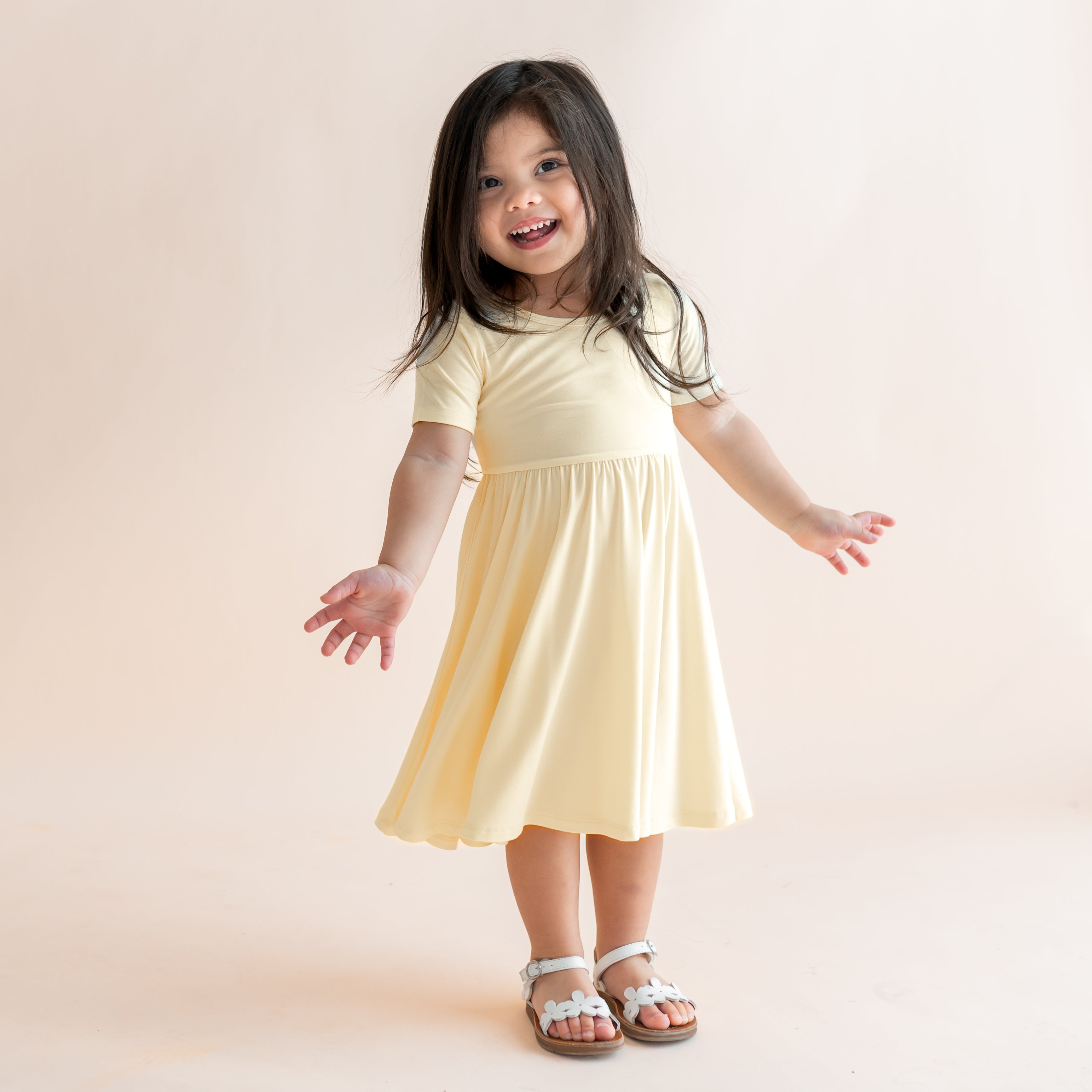 Child wearing a light yellow short sleeve twirl dress