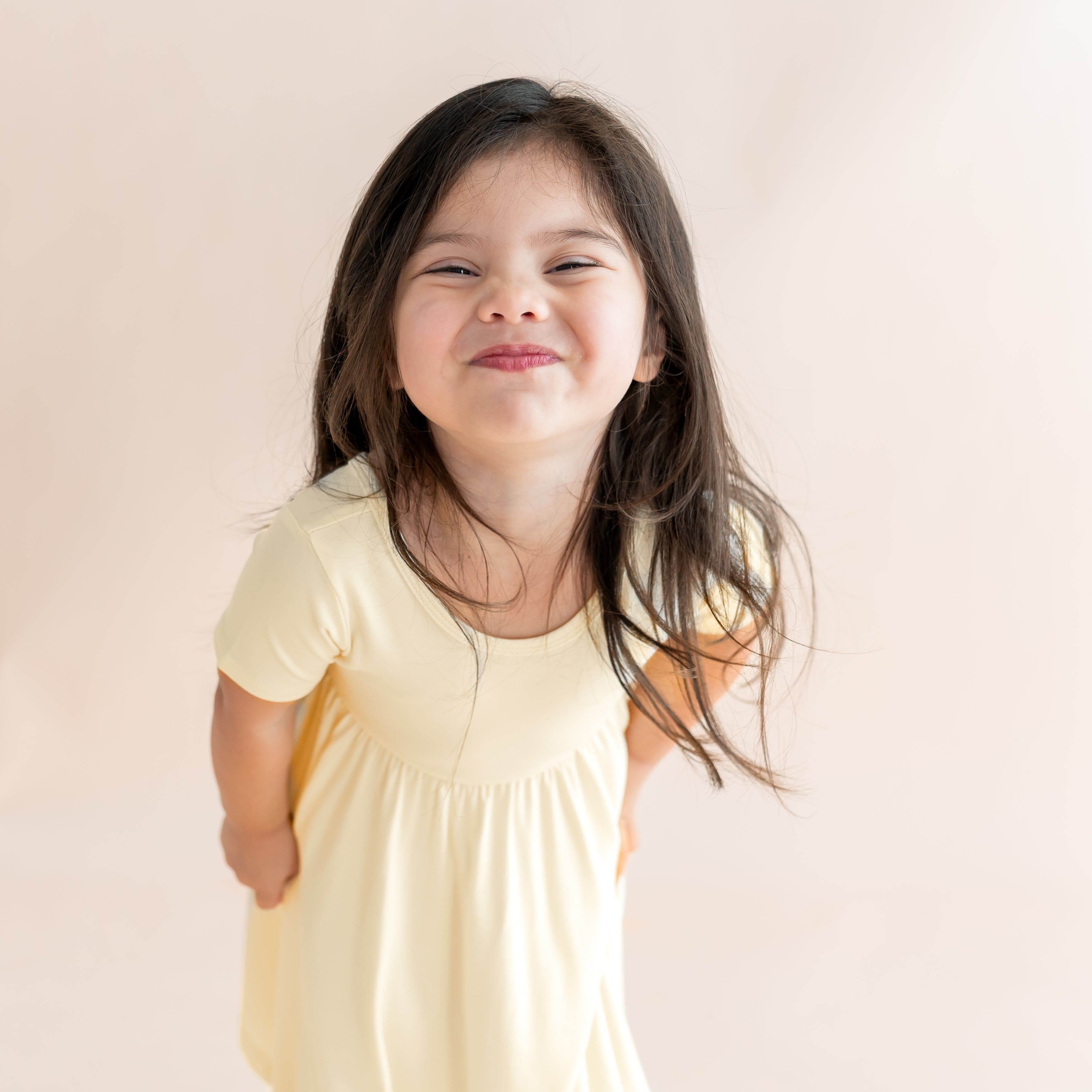 Young girl wearing a yellow dress against a plain background