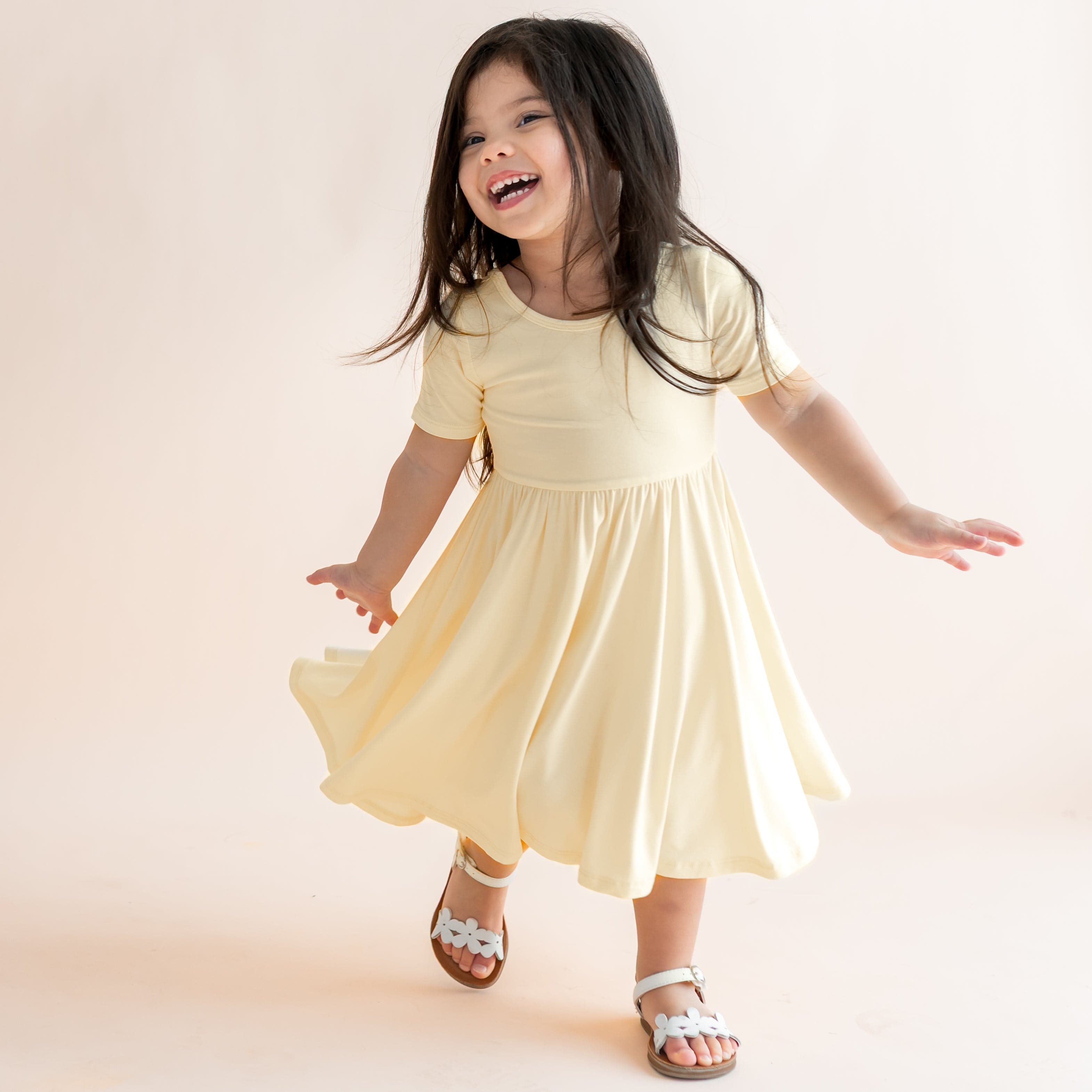 Child in a yellow dress standing on a light background