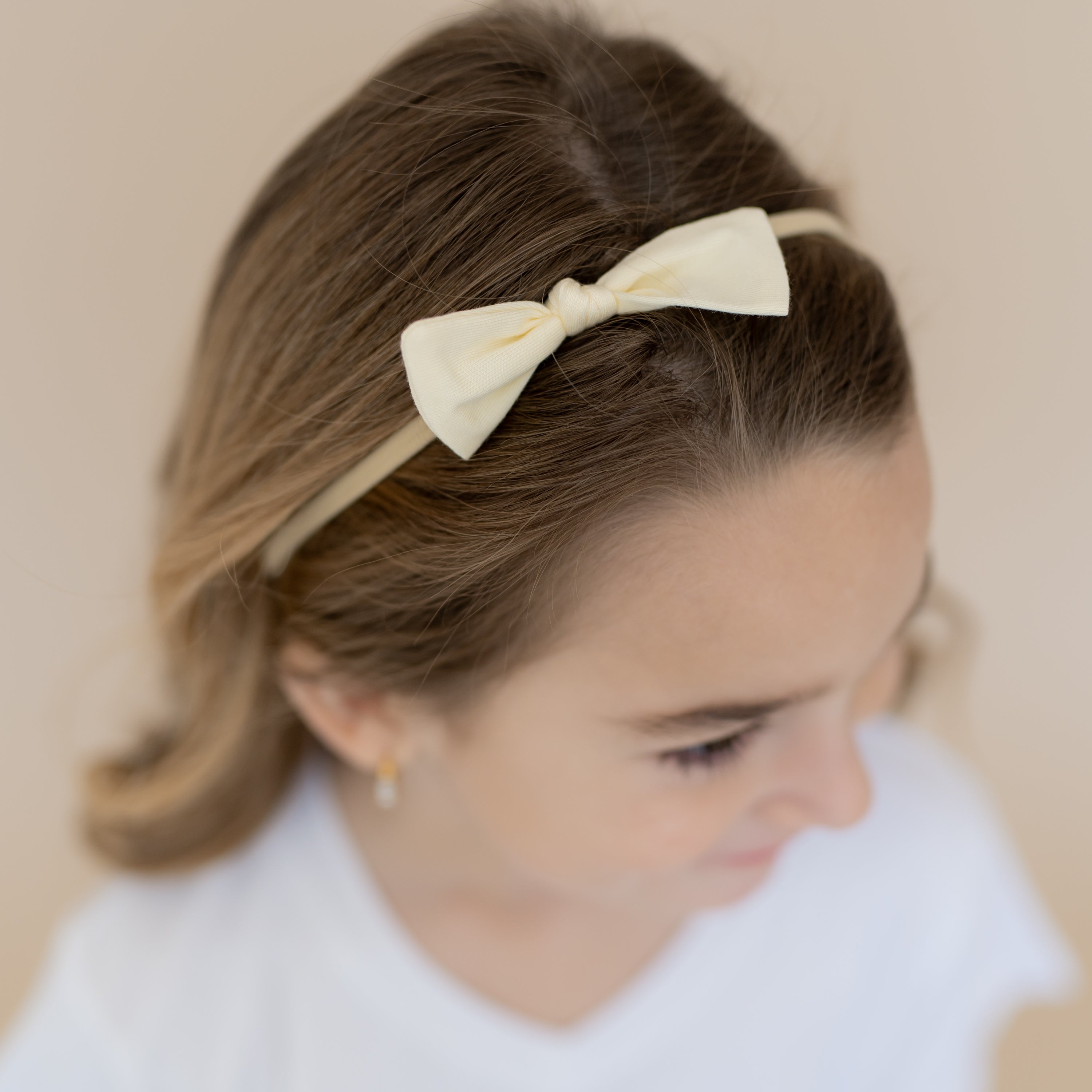 Close up of the Tiny Nylon Bow in Chamomile on a young model