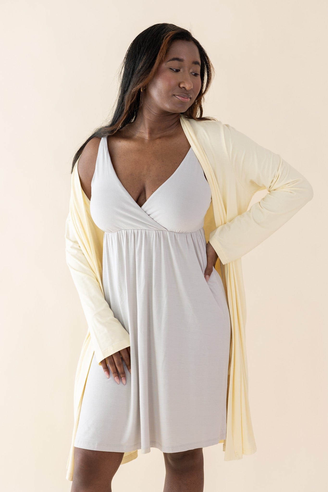 Woman wearing a cream dress with a yellow robe on a beige background