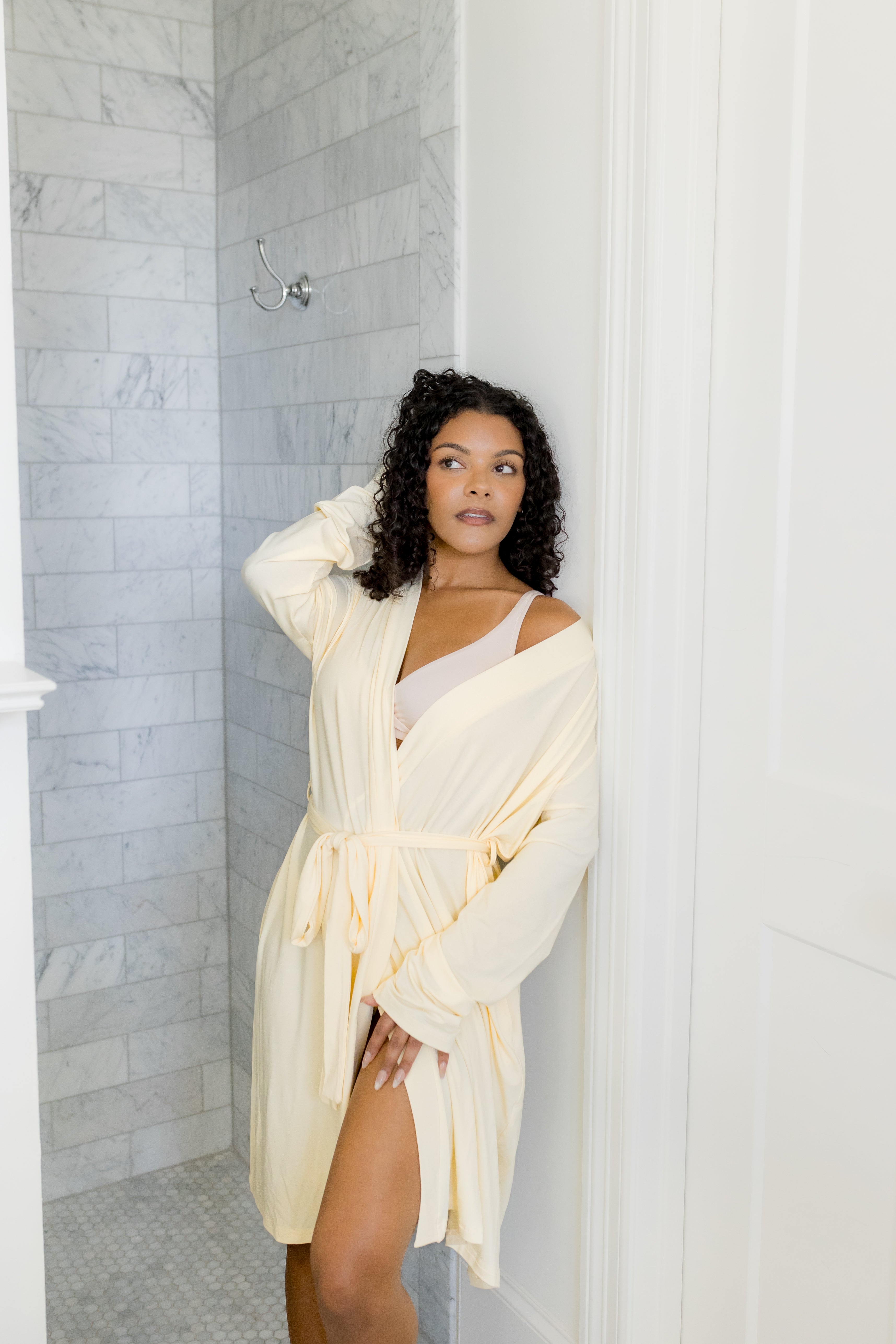 Female modeling the Women's Lounge Robe in Chamomile leaning against a wall in the bathroom