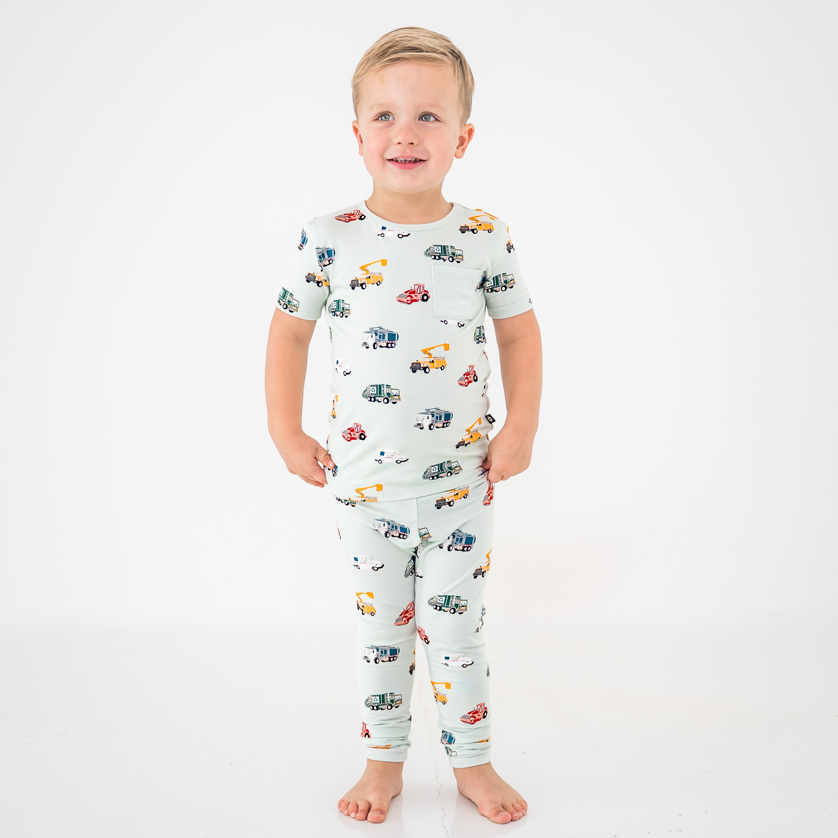 Young boy standing in front of a white background wearing the Short Sleeve with Pants Pajamas in City Vehicles