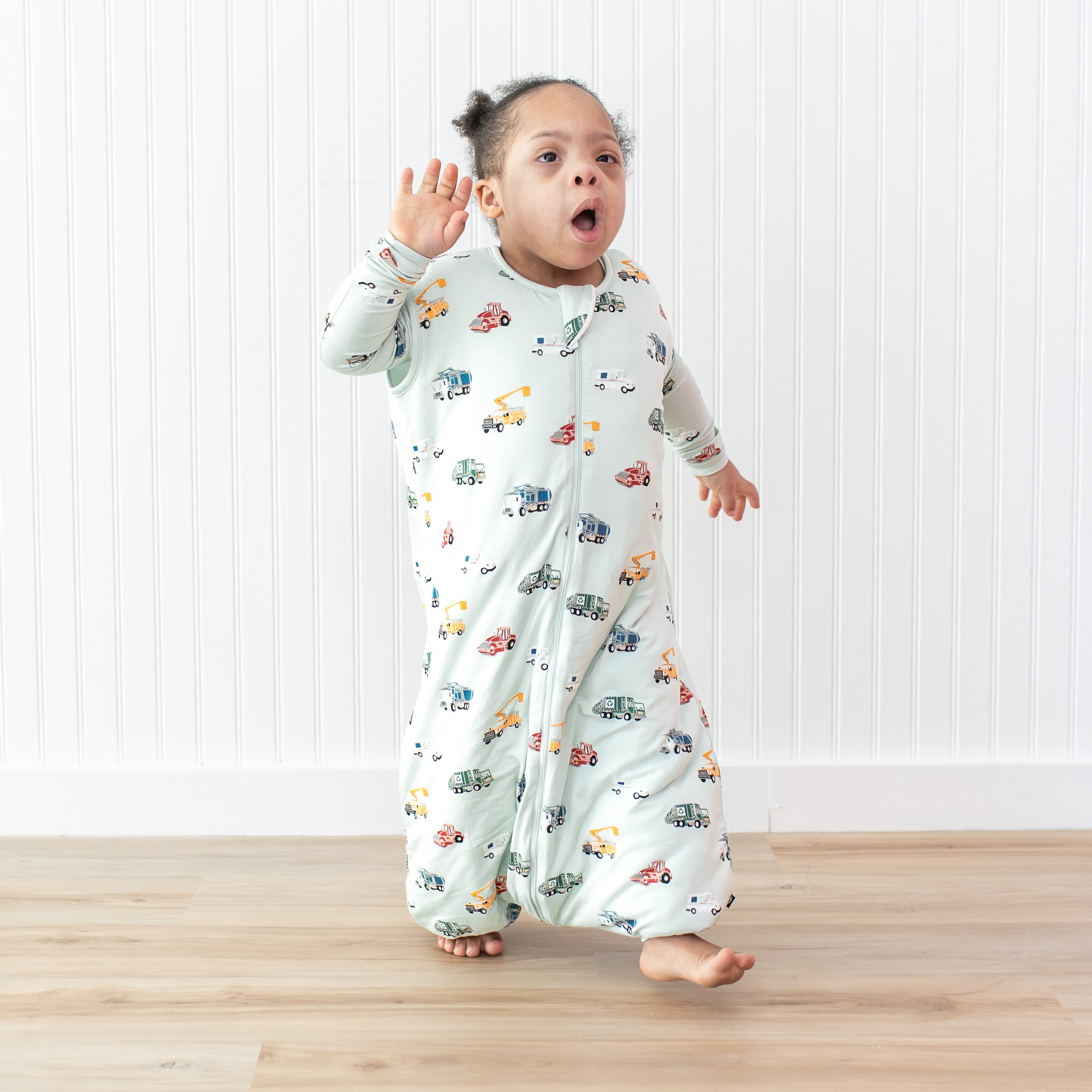 Young child walking in front of a white paneled wall wearing the Sleep Bag Walker in City Vehicles 1.0