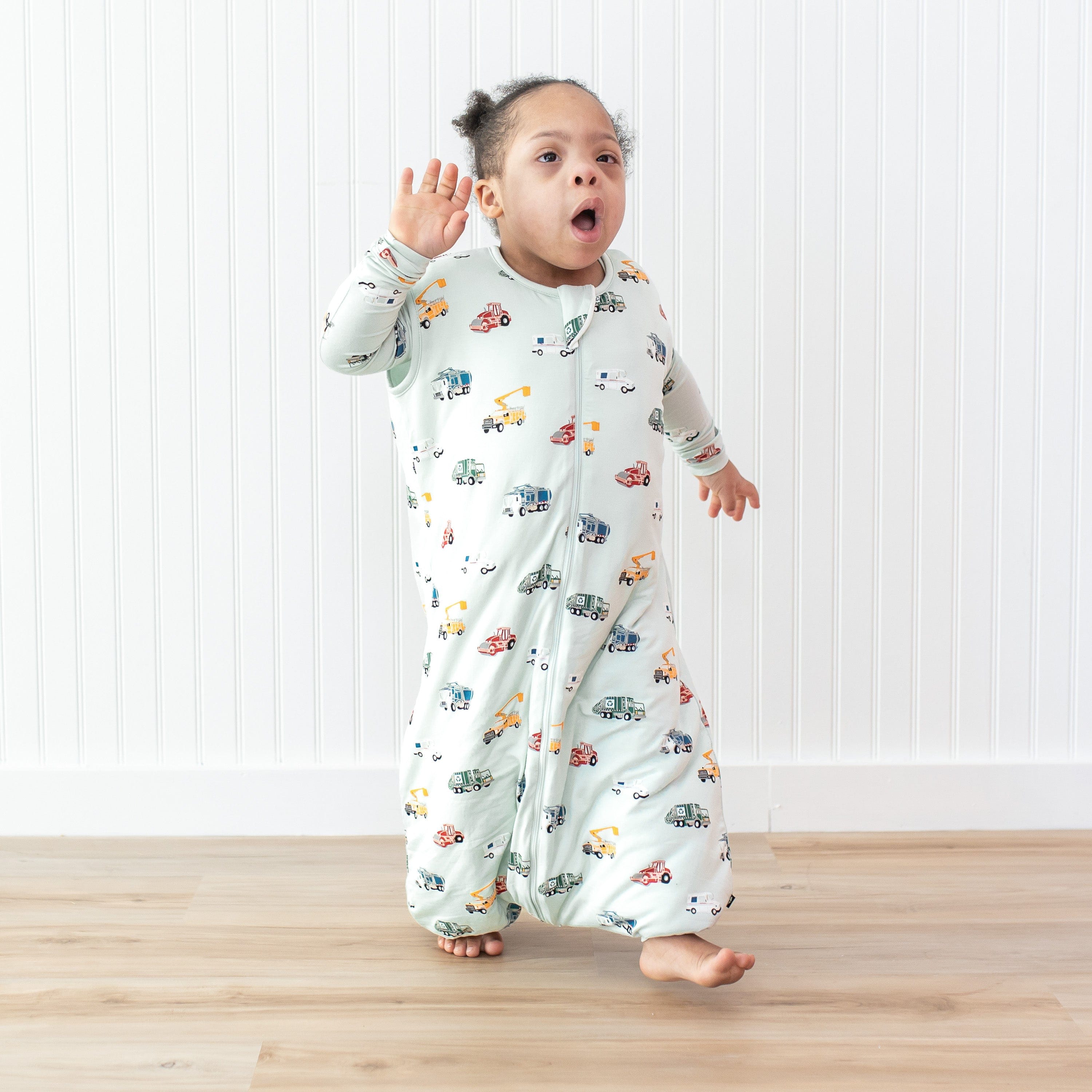 Young child walking in front of a white paneled wall wearing the Sleep Bag Walker in City Vehicles 1.0