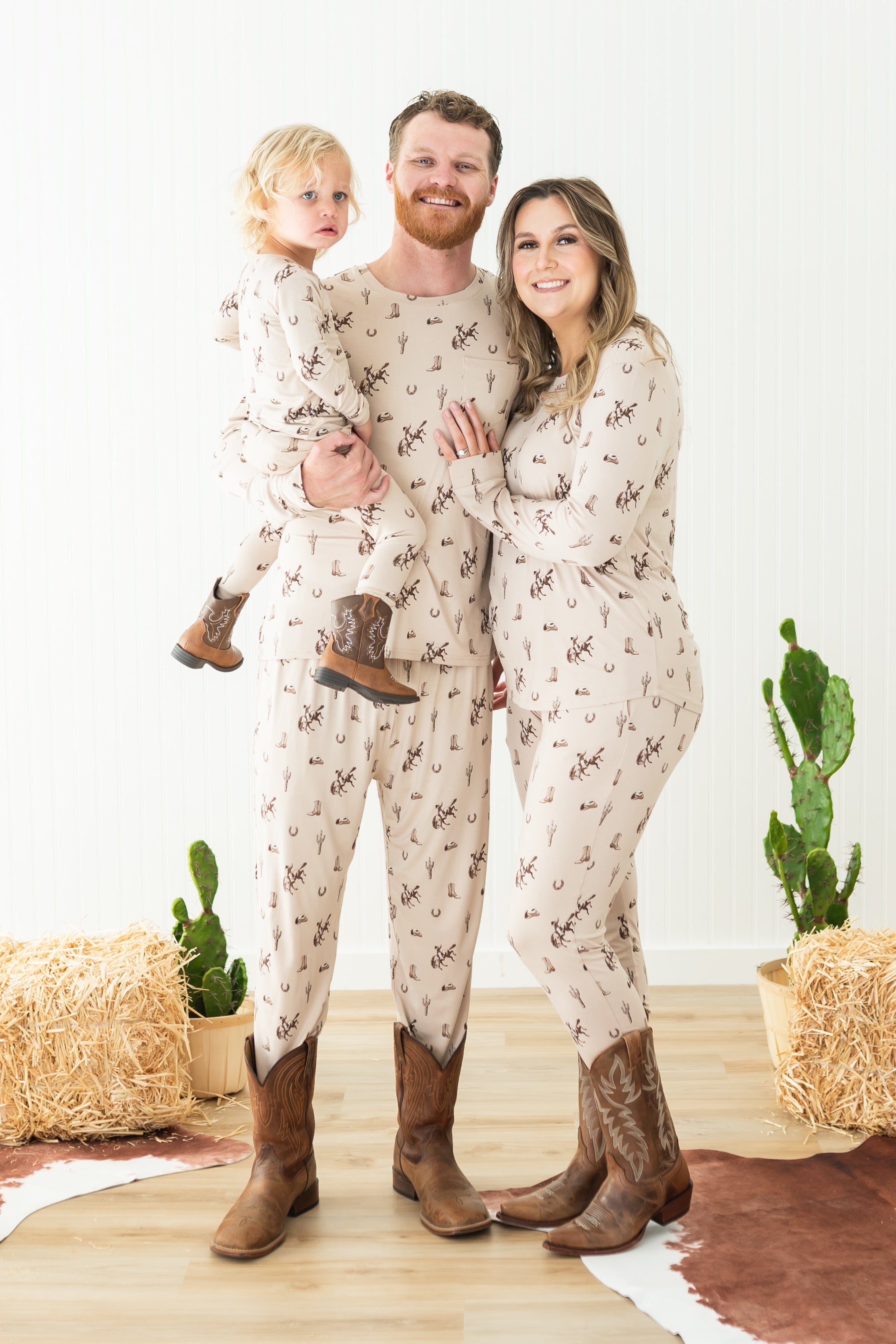 Family of three wearing matching Classic Cowboy pajamas and brown cowboy boots