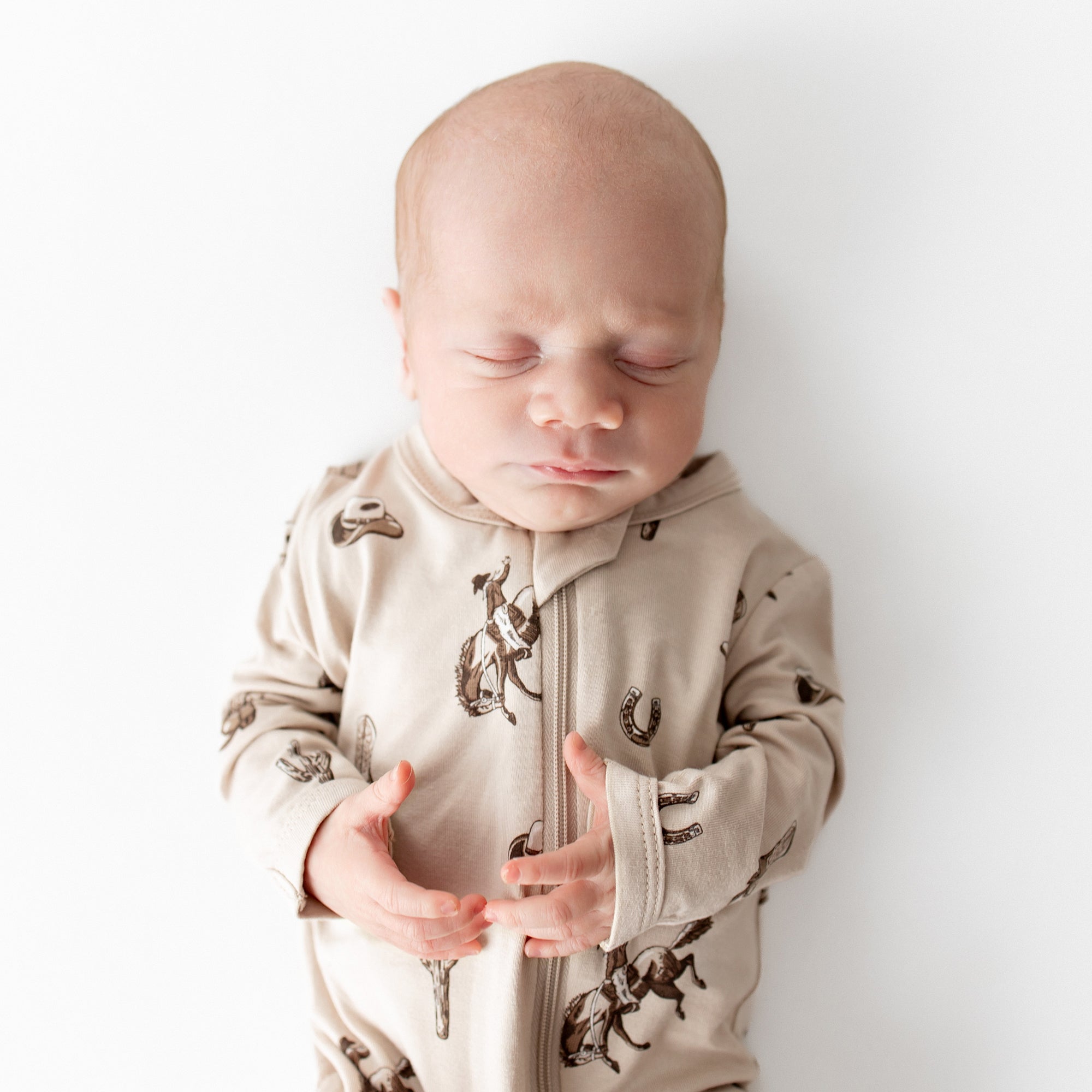 Close up of sleeping infant wearing the breathable Zippered Footie in Classic Cowboy from Kyte Baby