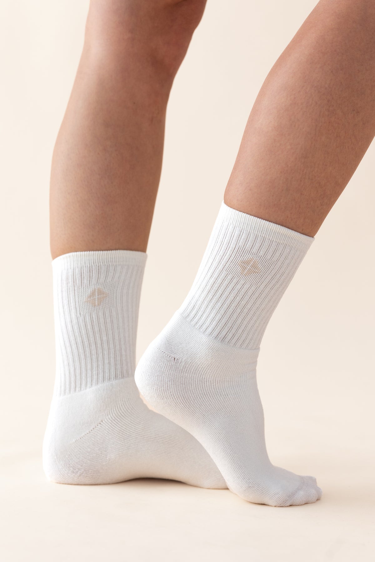 Adult Crew Socks in Cloud shown on the feet of a model with the Kyte logo visible