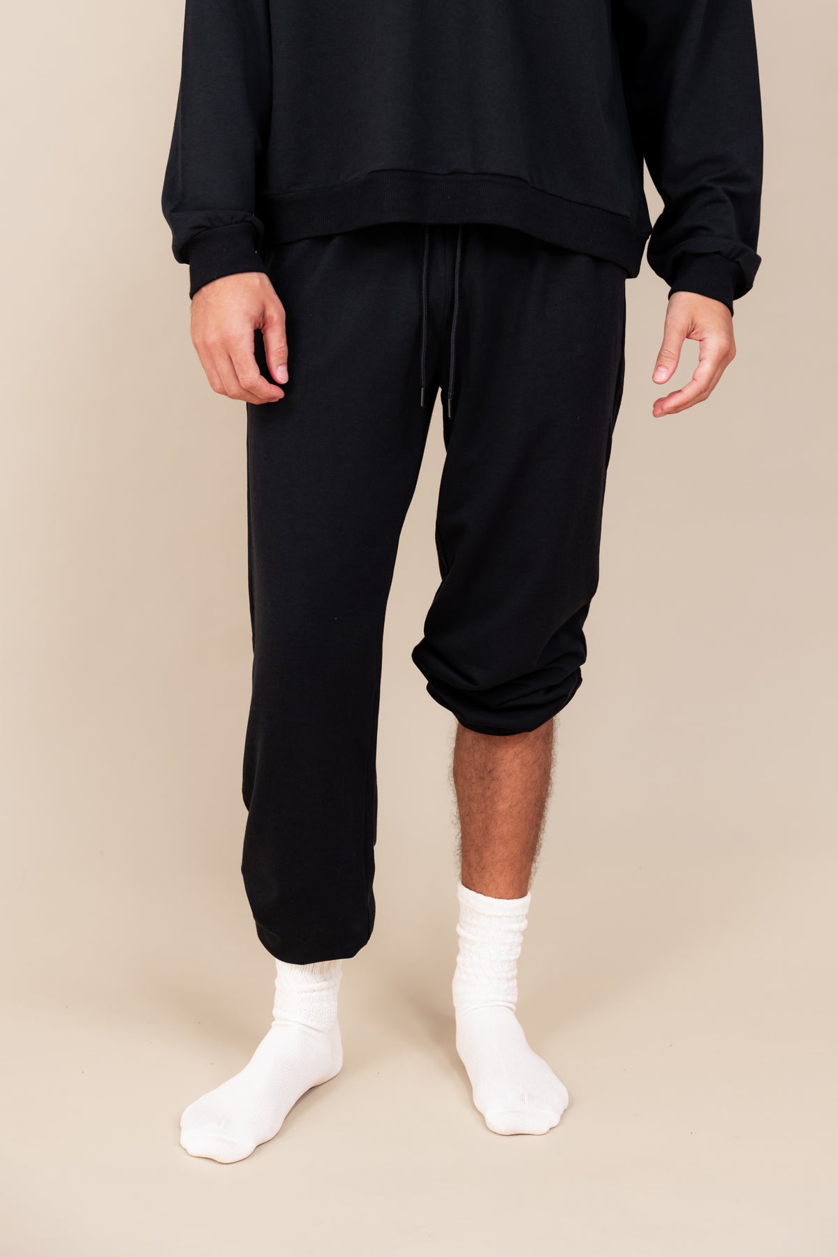 Modal wearing Adult Scrunch Socks in Cloud color on black jogger set on a beige background