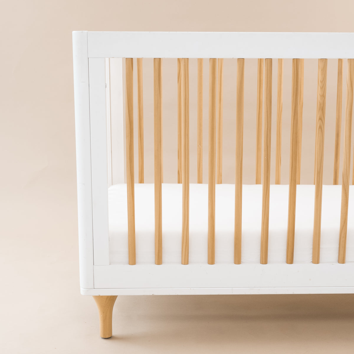 Crib Sheet in Cloud shown on a mattress in a modern white and wooden crib