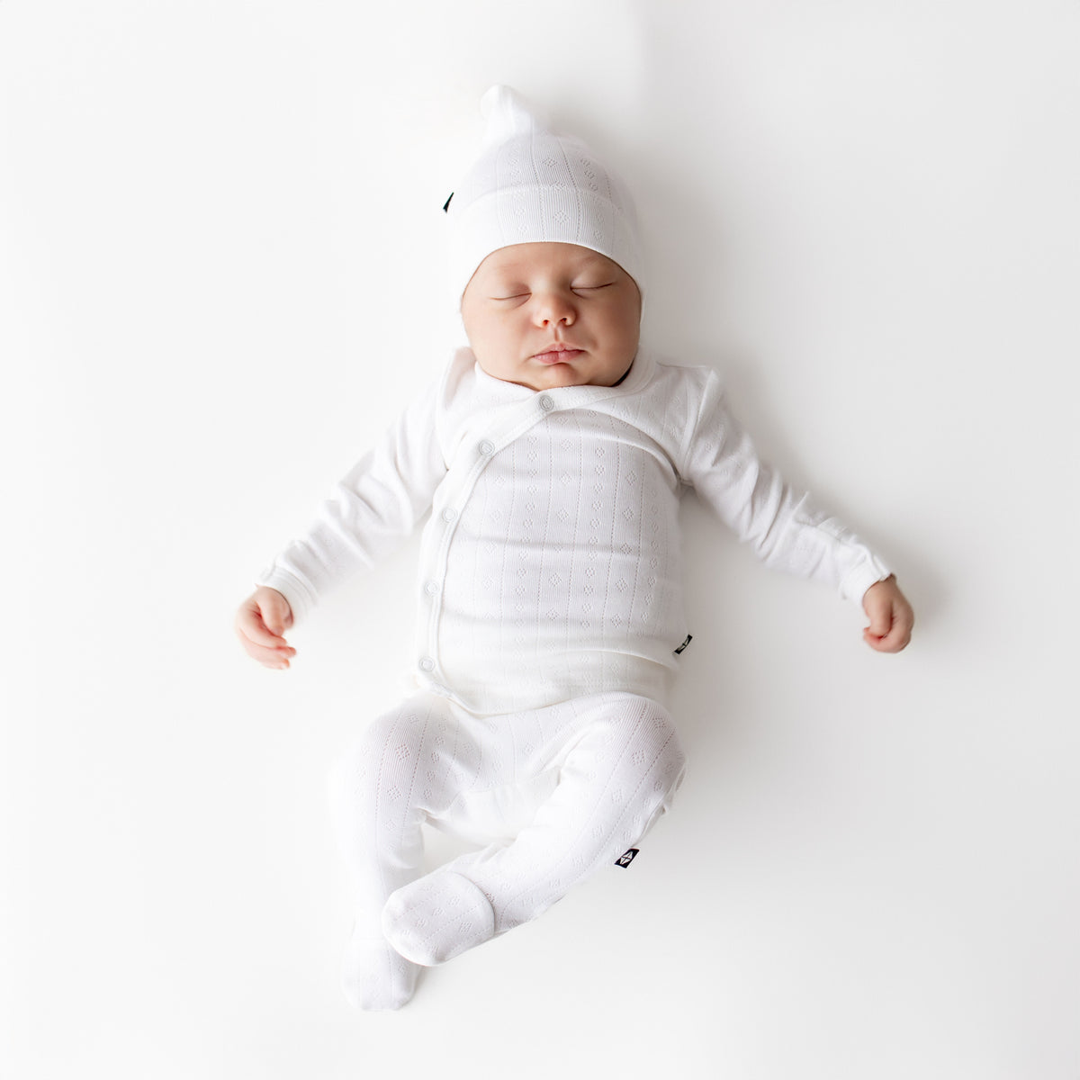 Sleeping newborn wearing the Pointelle Take Me Home Set with Cap in Cloud
