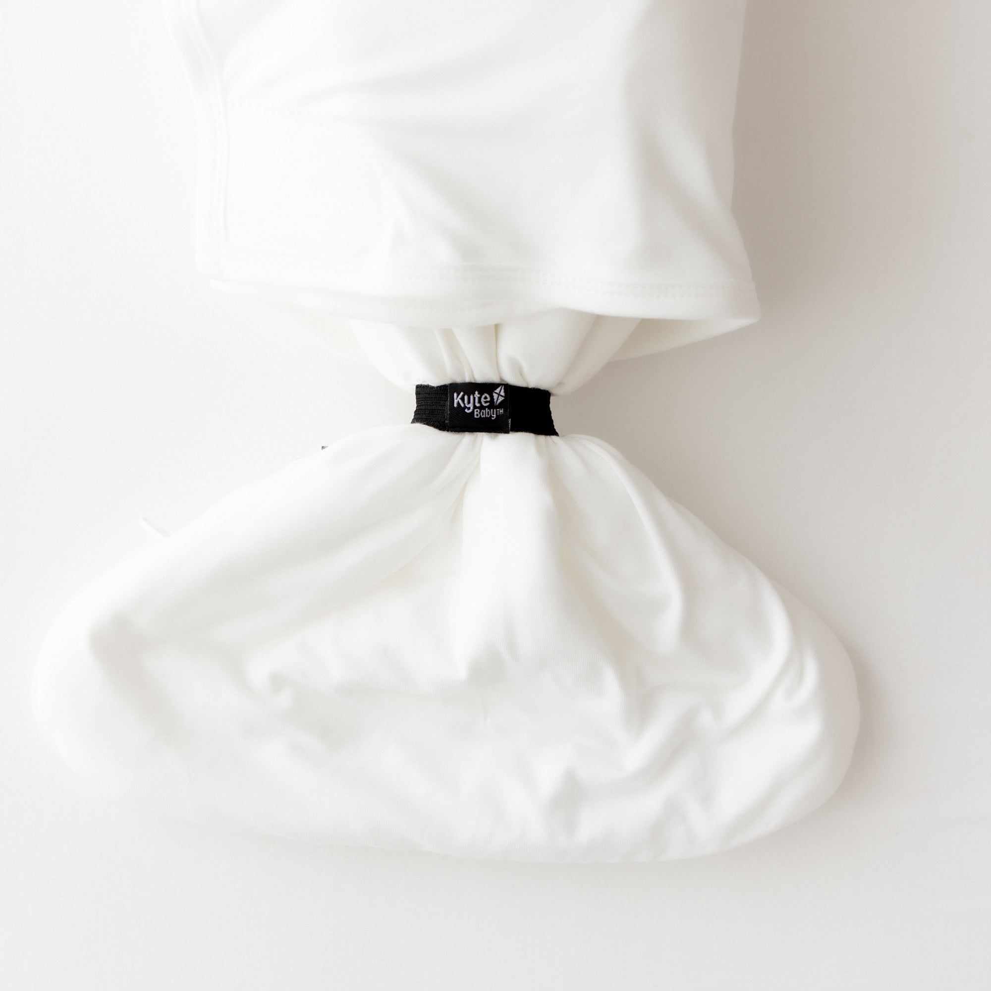 White bamboo sleep bag swaddler with a black elastic on a white background