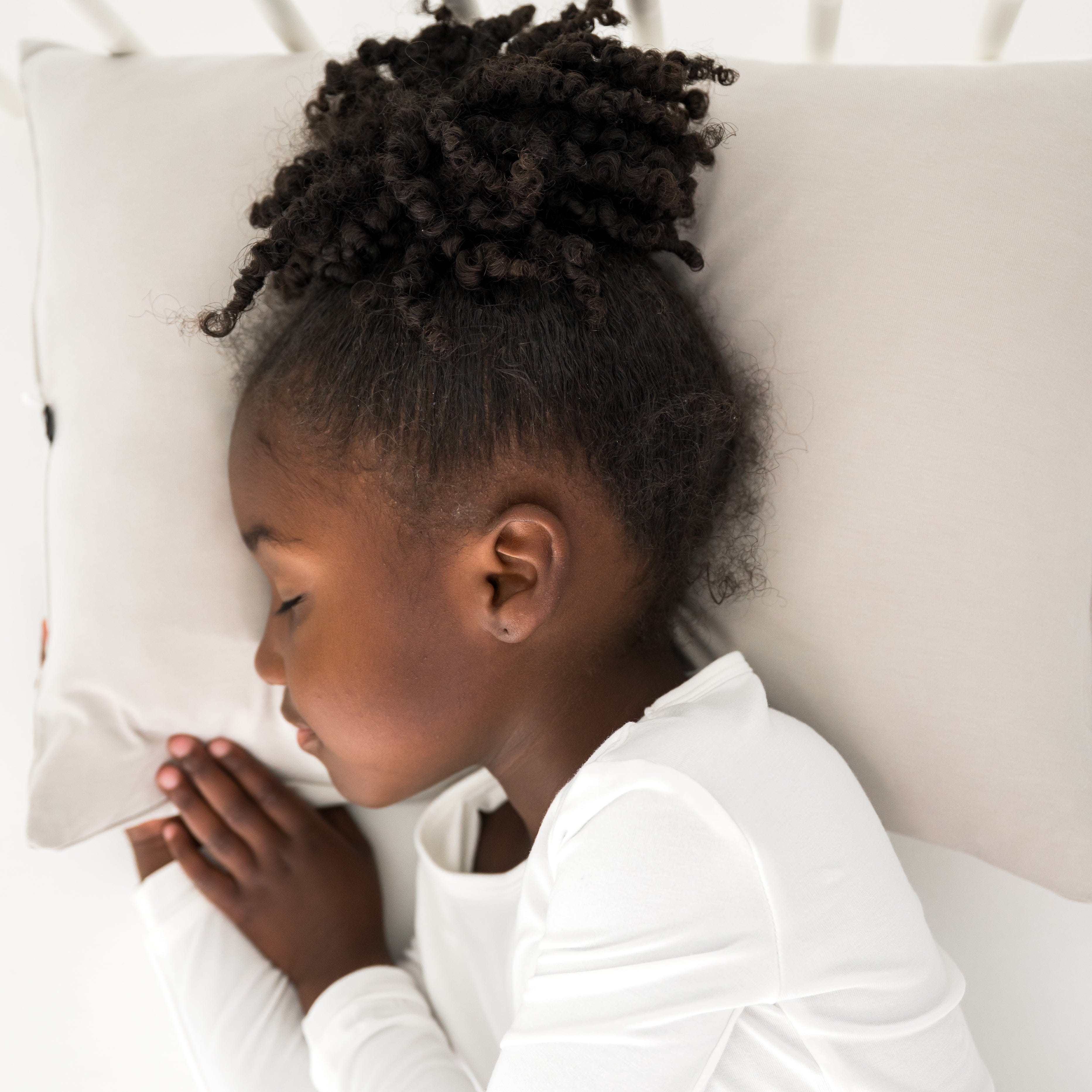 Young girl lying on a cream pillow with a neutral background
