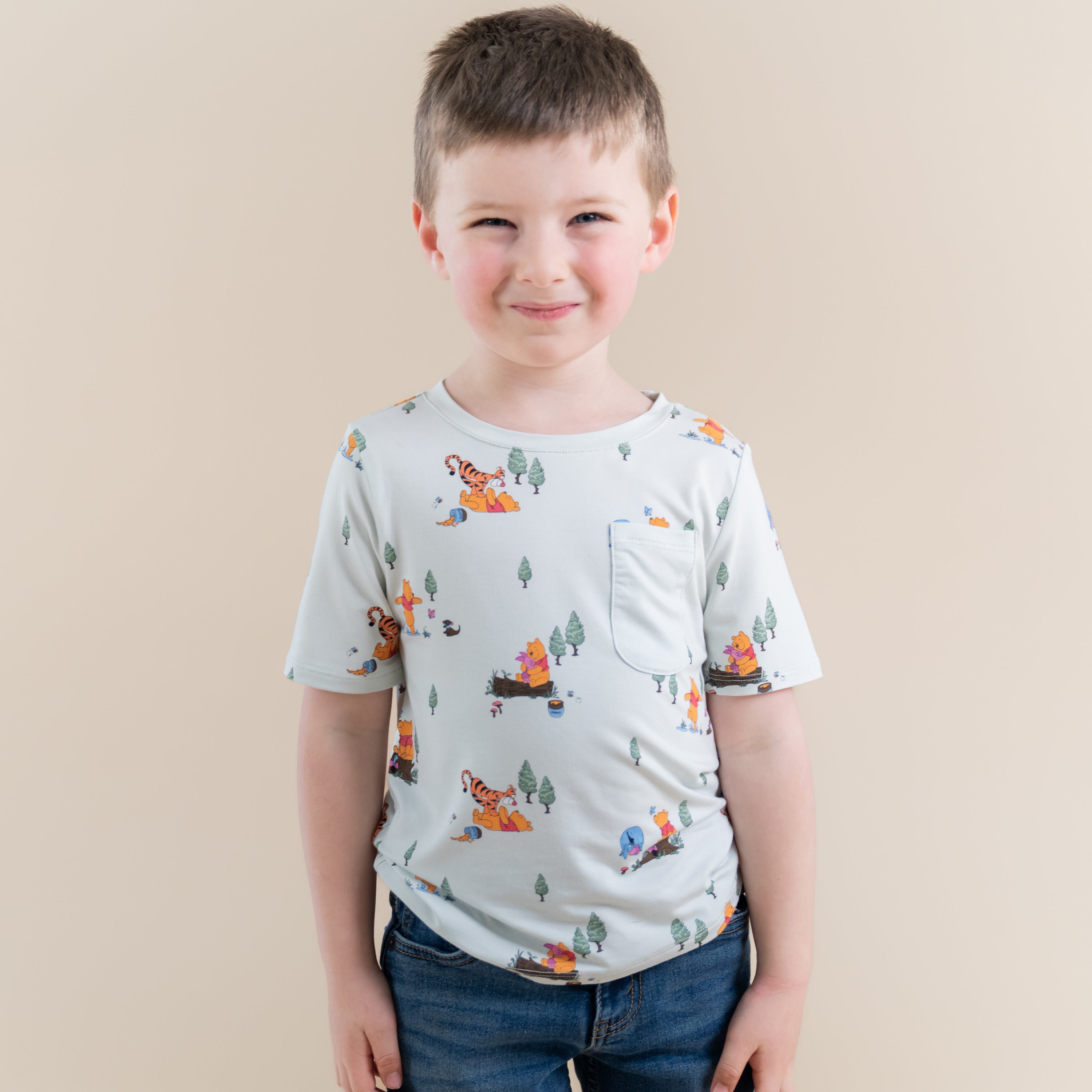 Young boy smiling wearing the Toddler Crew Neck Tee in Winnie the Pooh Hundred Acre Wood