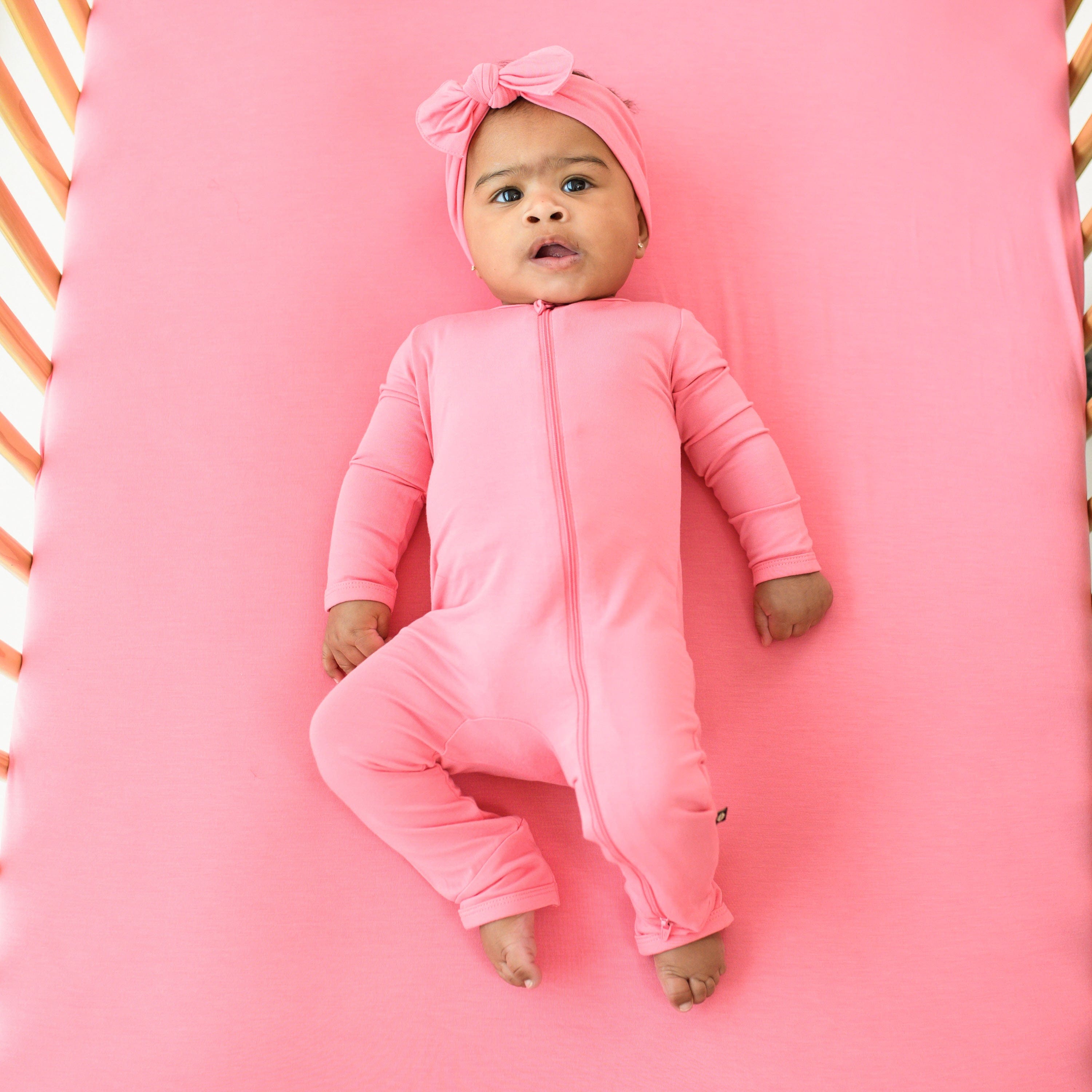 baby in zippered romper and bow in color guava