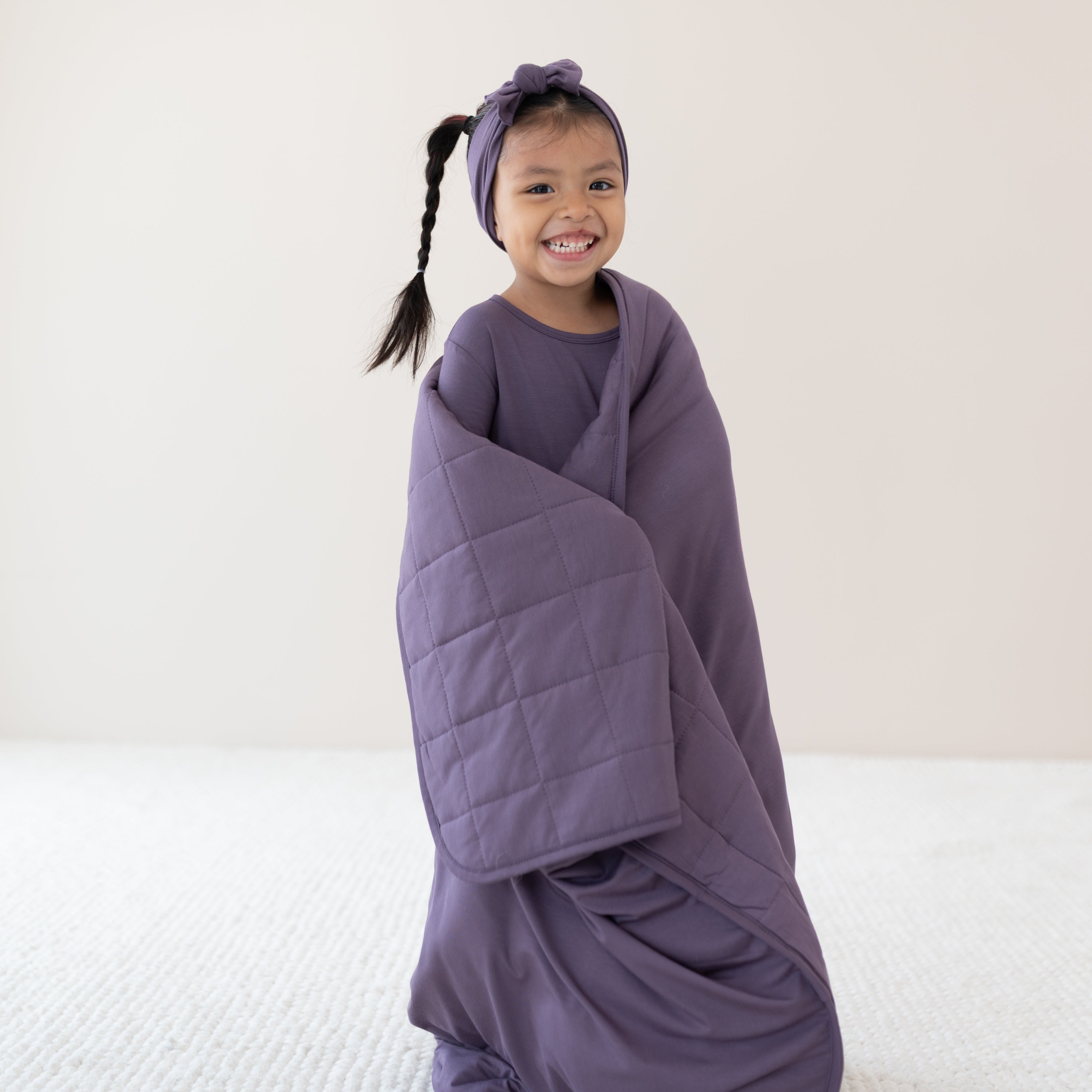 Close up on smiling child wrapped in Youth Blanket in Currant 2.5