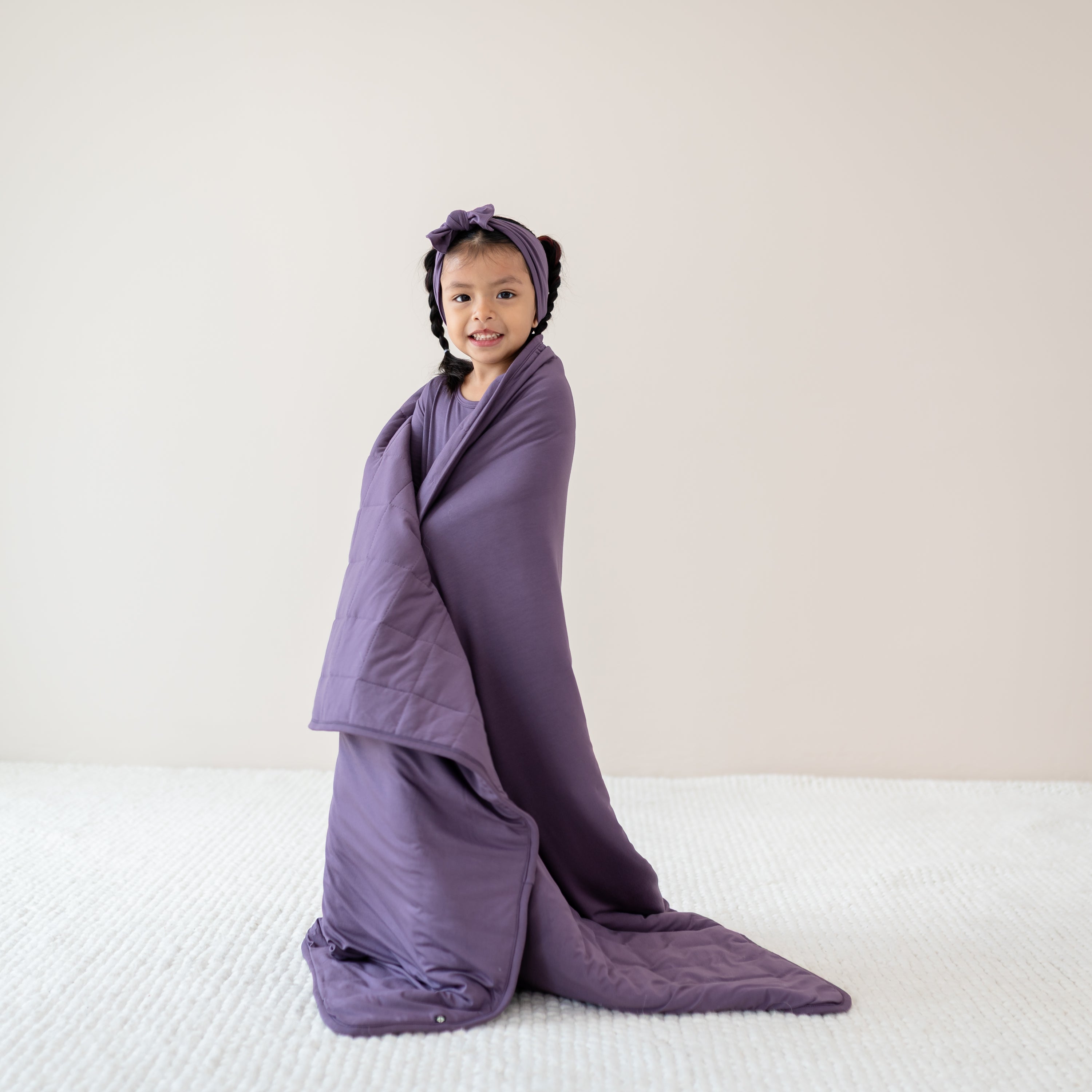 Child with Currant Bow and Pajamas on wrapped in Youth Blanket in Currant 2.5