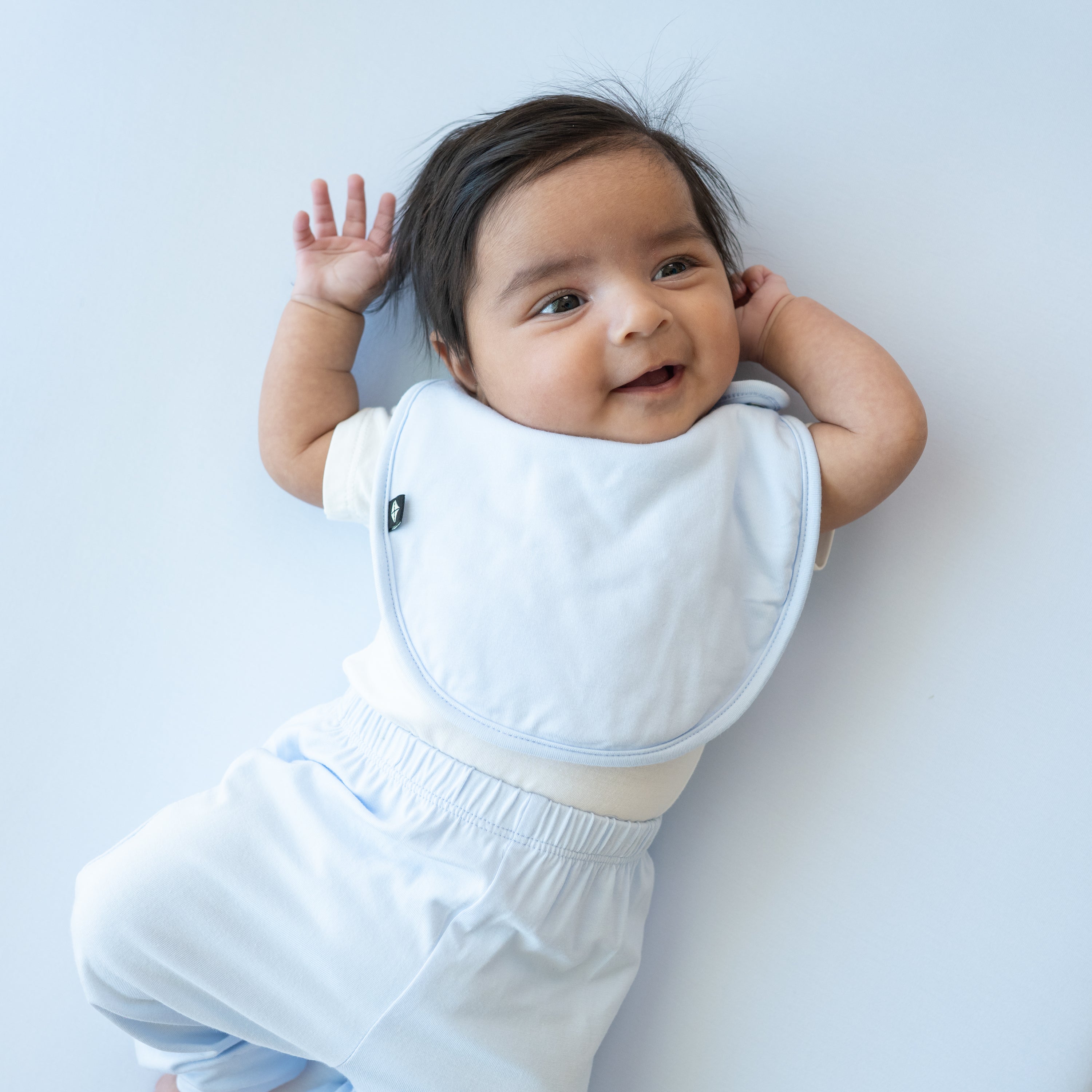 Infant model wearing the Cushy Bib in Mist with matching pants
