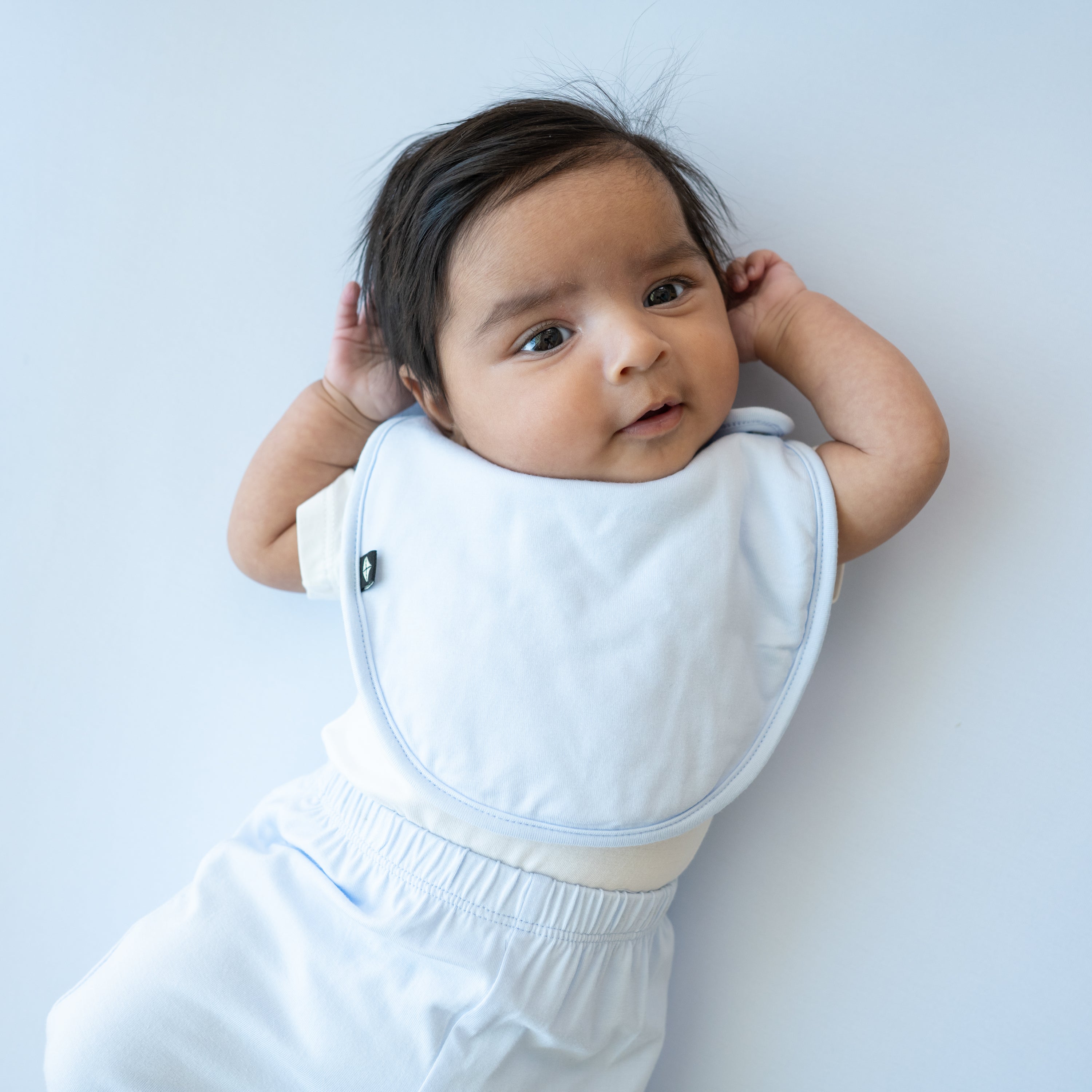 Infant model wearing the Cushy Bib in Mist with matching pants