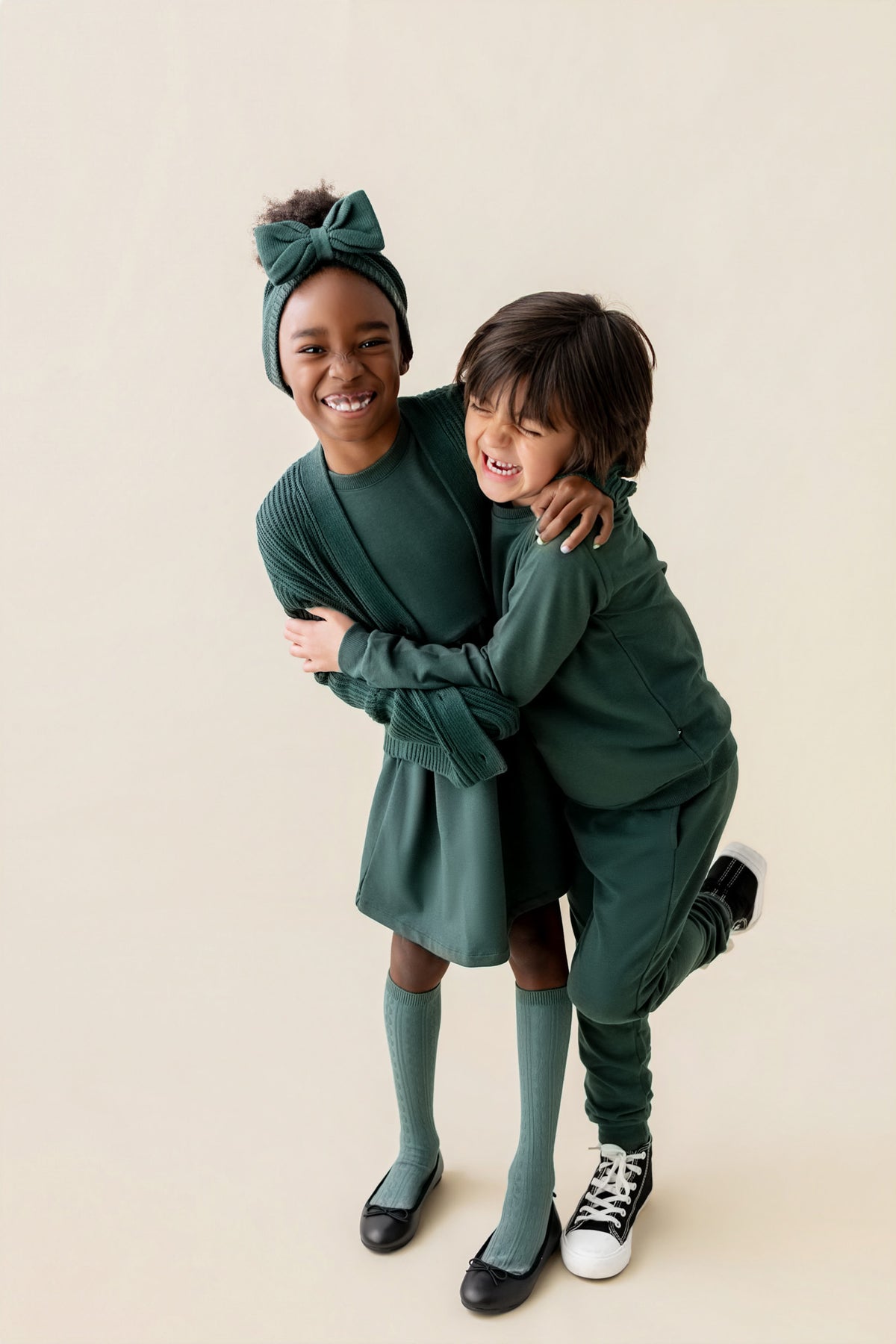 A boy wearing Long Sleeve Jogger Set in Cypress color and girl wearing Long sleeve skater dress in cypress color on a beige background