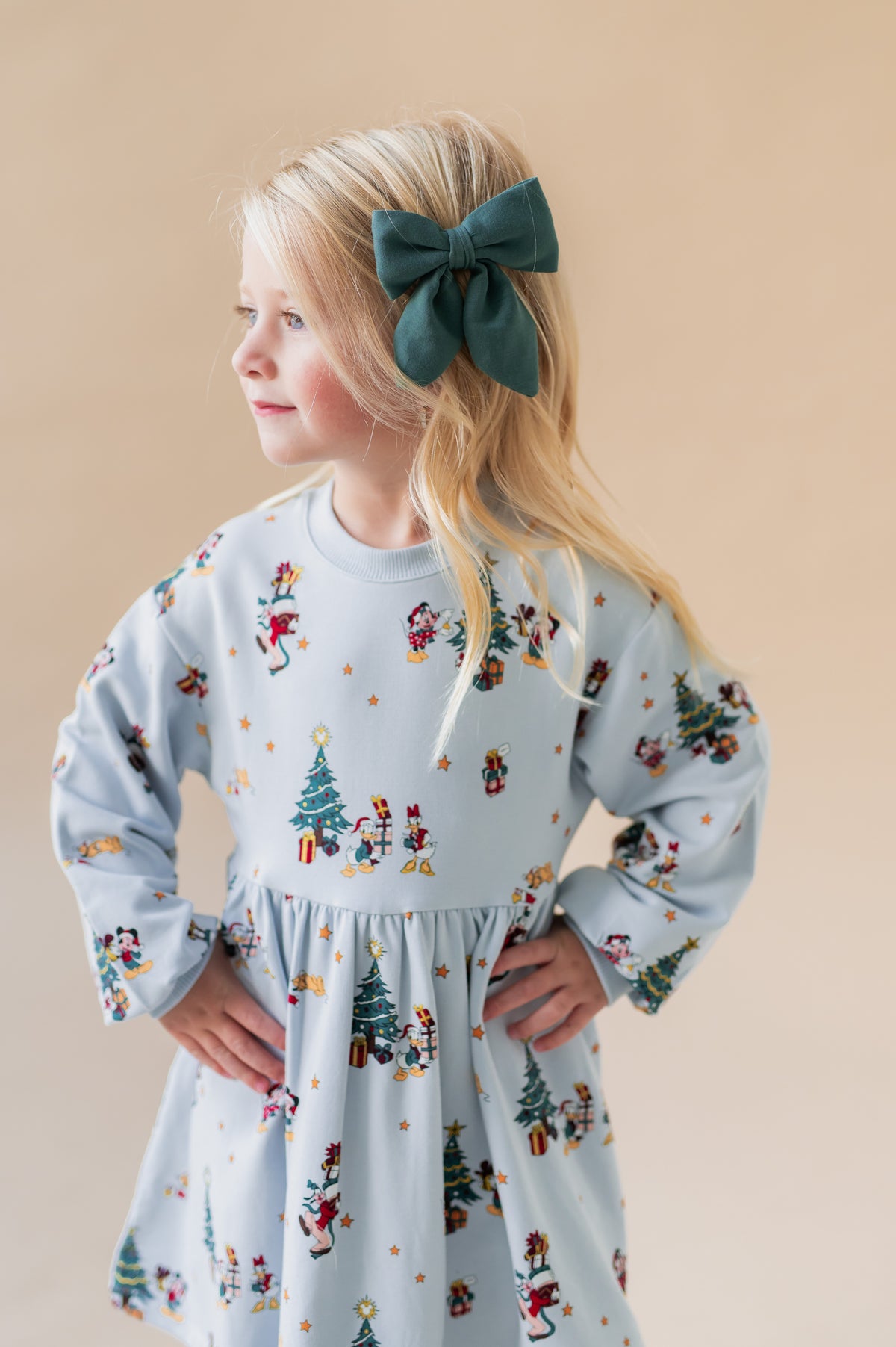 Girl wearing Medium Alligator Clip Bow in Cypress color in her hair on a beige background