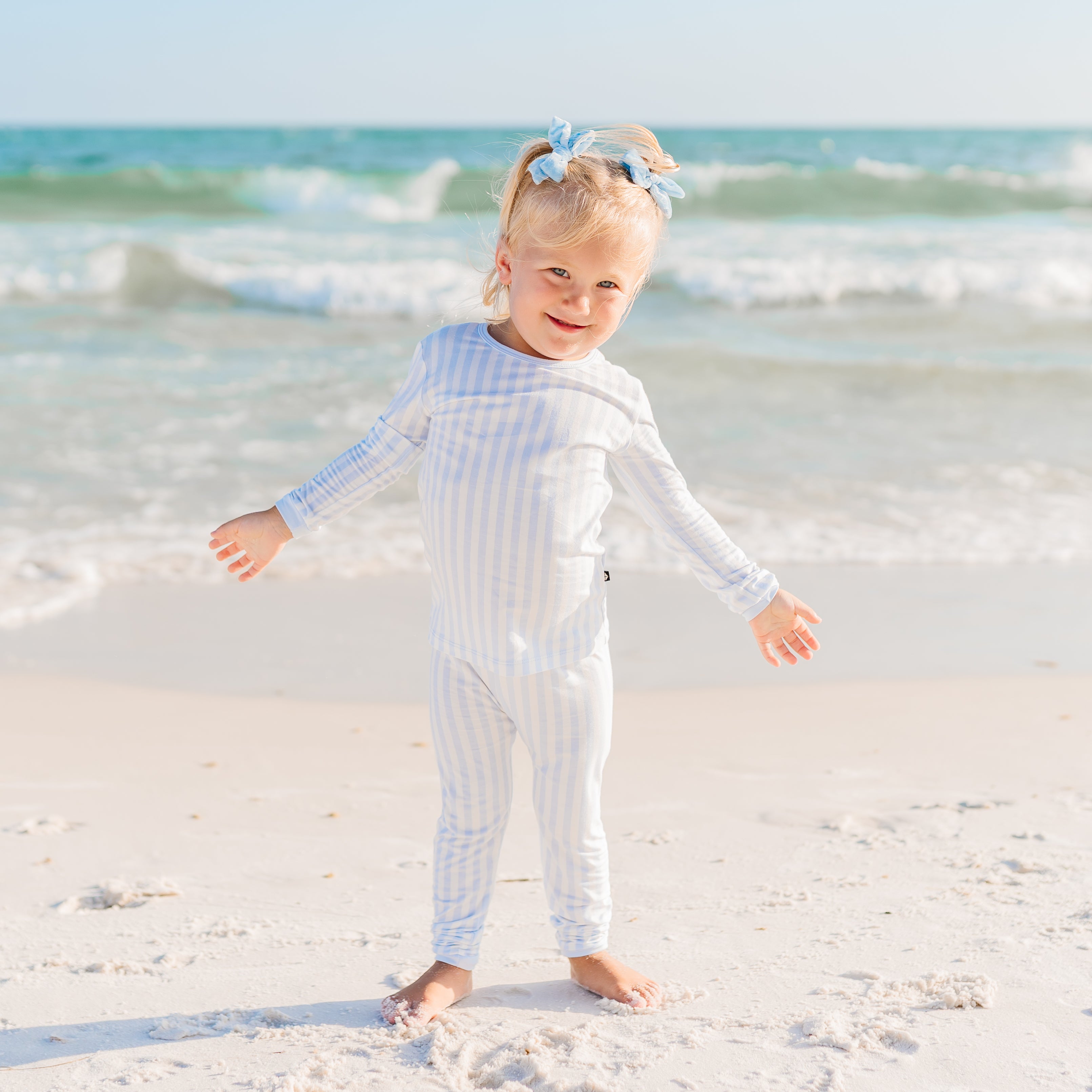 Toddler on the beach wearing mist stripe pajamas