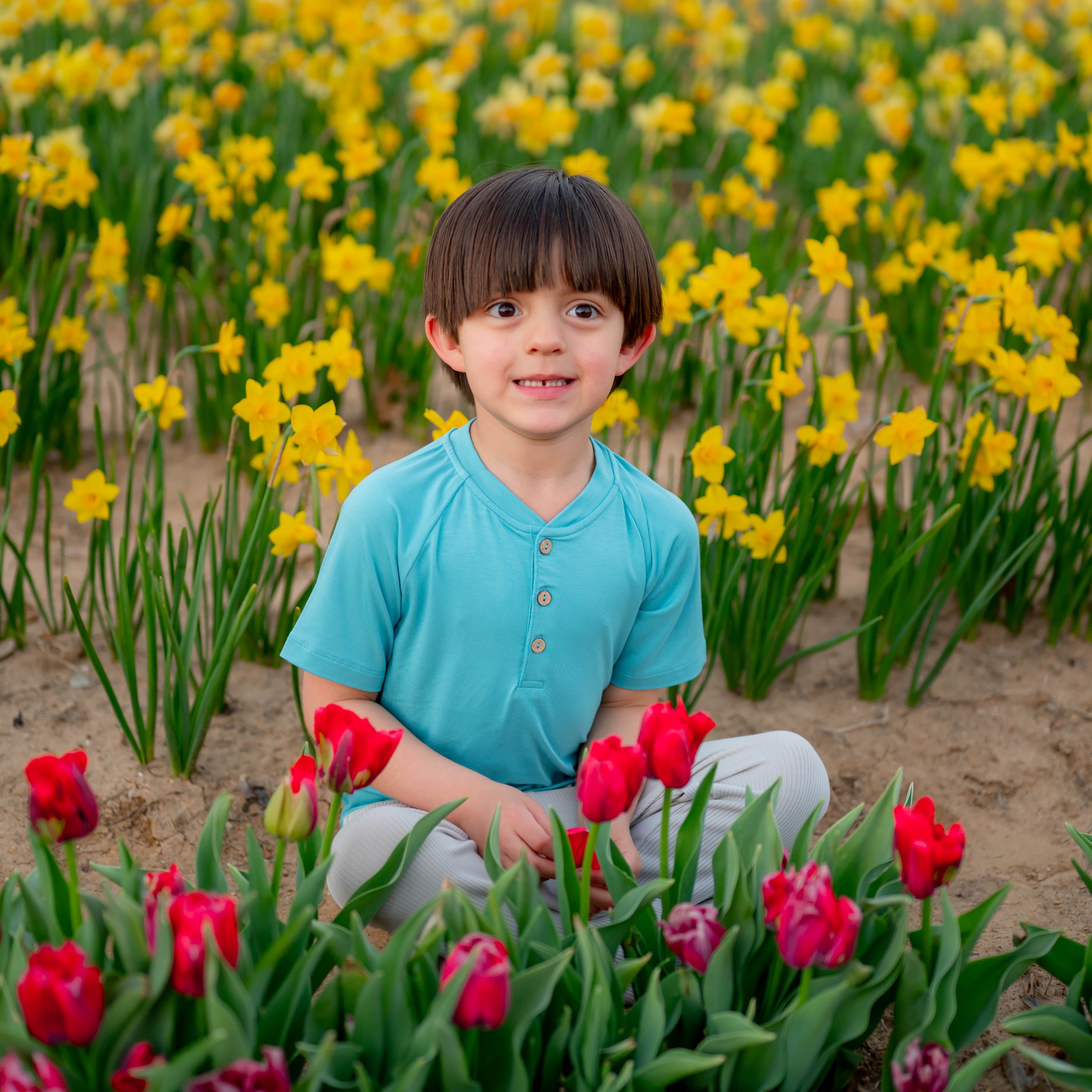 Toddler in Short Sleeve Toddler Henley Tee in Makai in tulip field