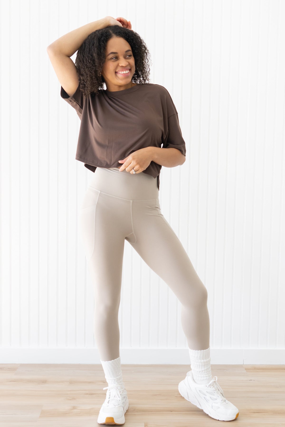 Model wearing brown cropped tee and cream leggings with white sneakers