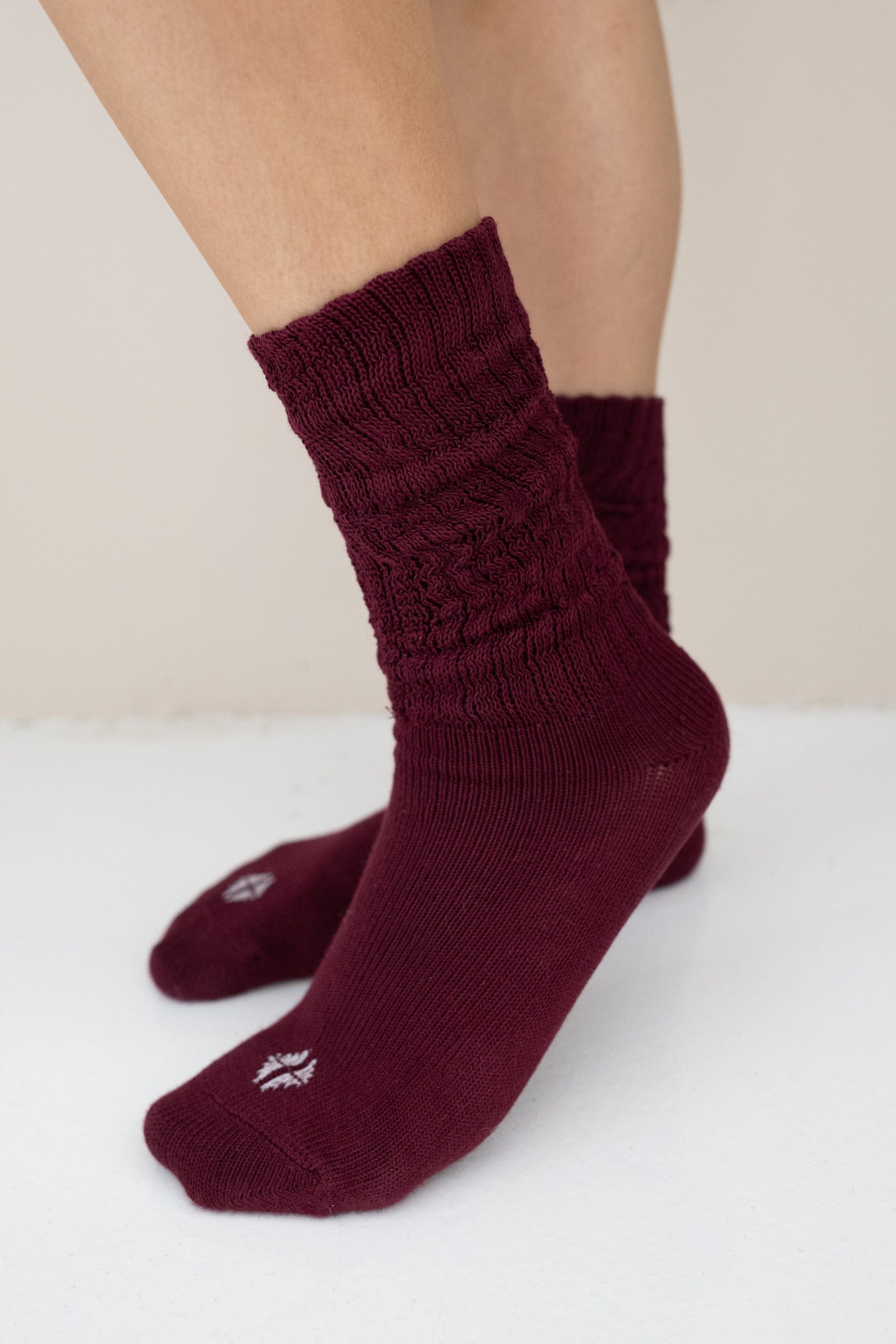 Burgundy socks worn by a person on a white surface with a beige background