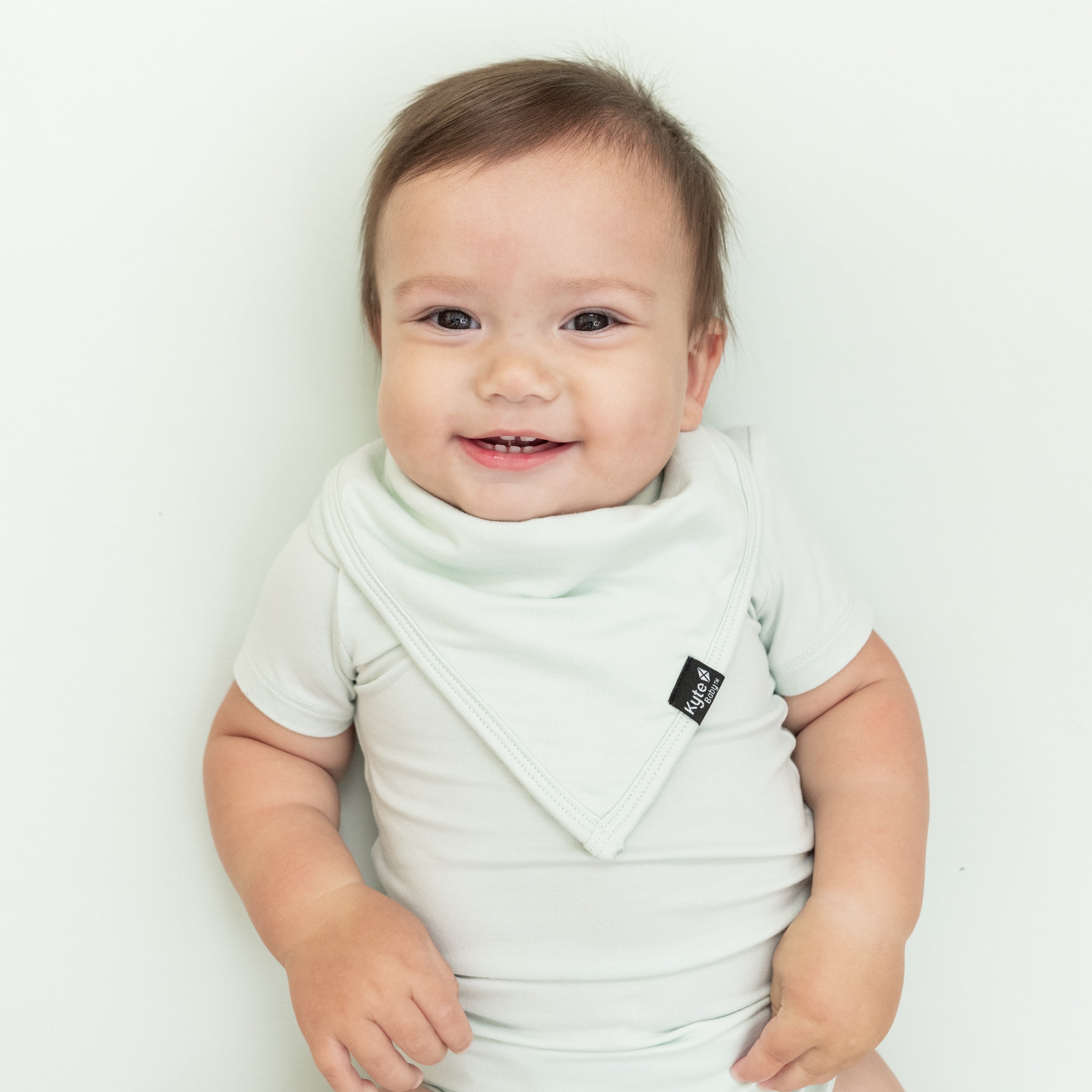 Smiling infant wearing the Bib in Dew with matching bodysuit
