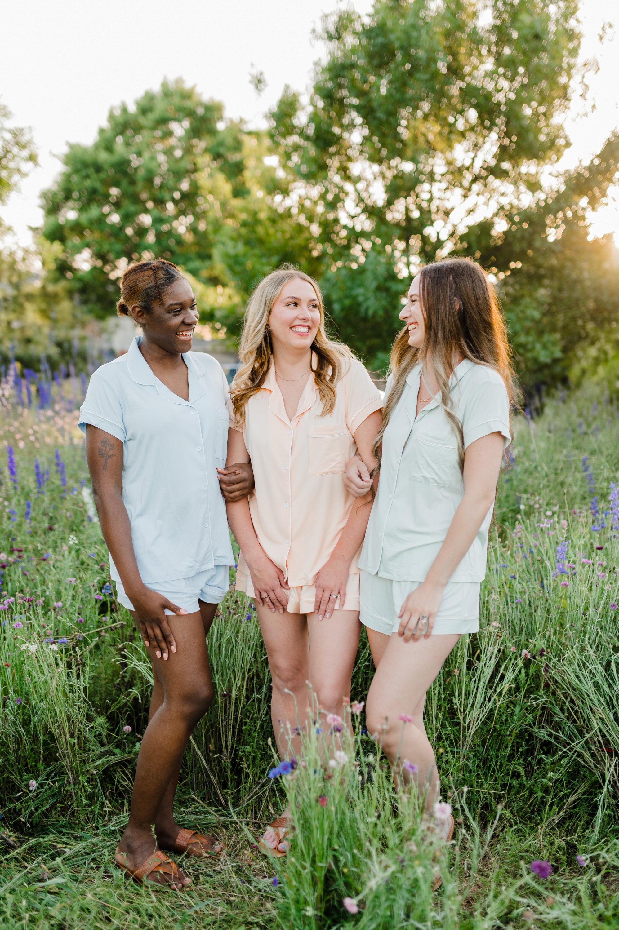Three smiling female models standing in a flower field wearing the Women's Short Sleeve Pajama Set in Summer 2025 solids