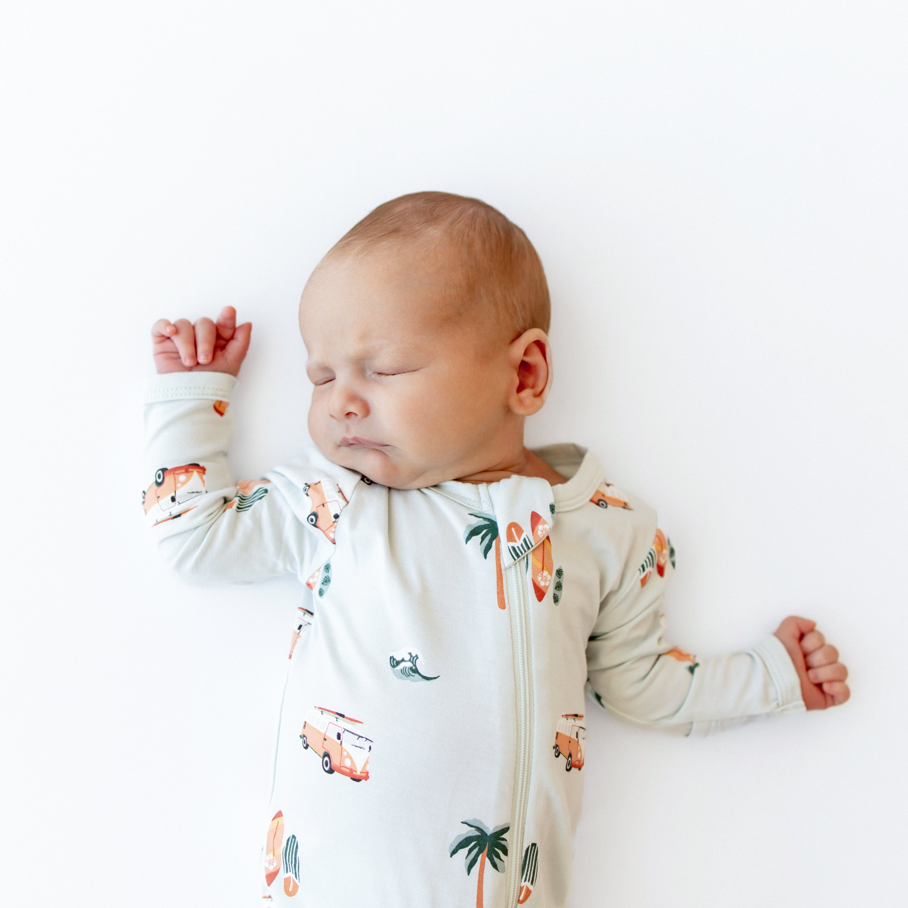 Sleeping baby with one hand up over their head with the other off to the side wearing Zippered Footie in Dew Surf