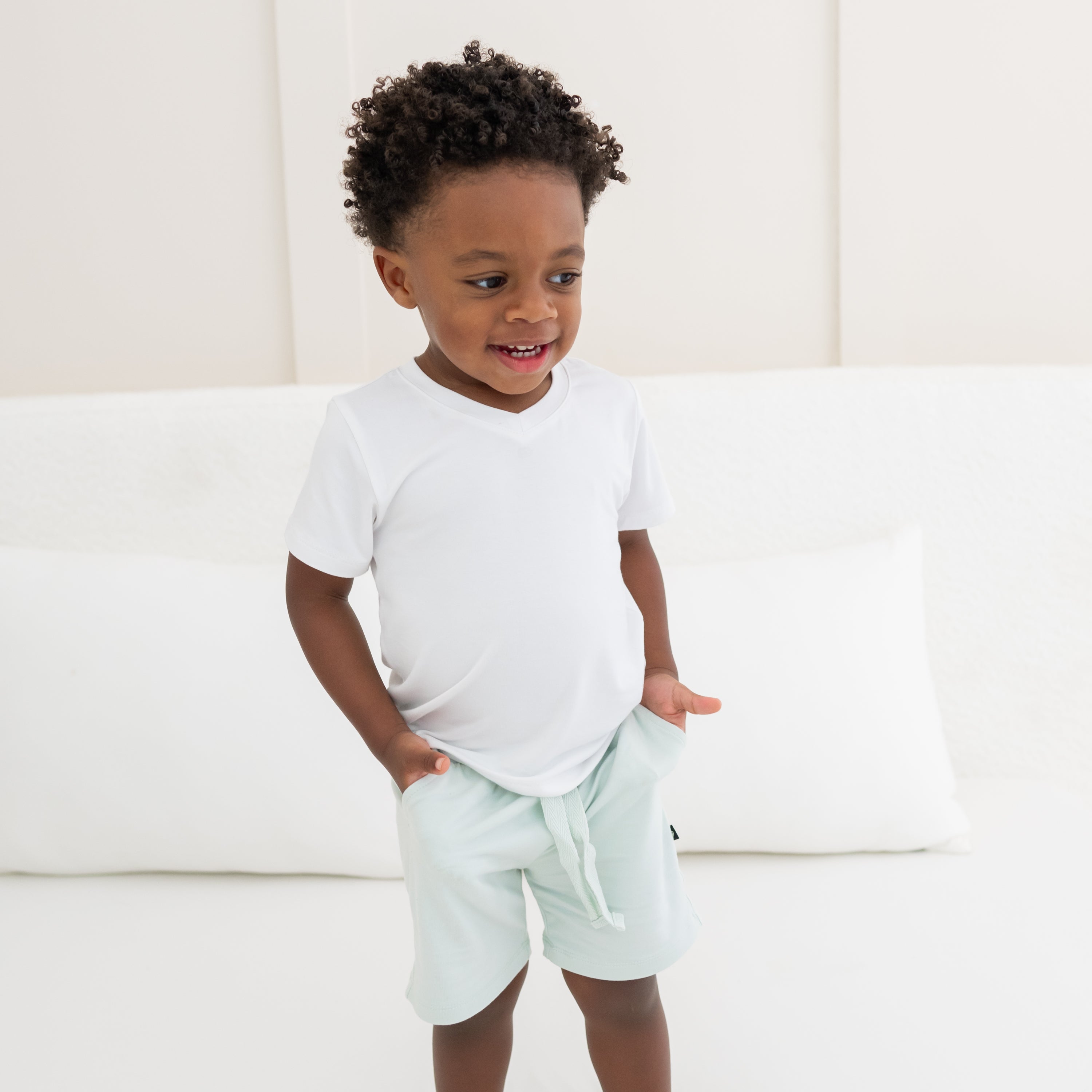 Kid with his hands in the pockets
of the Drawstring Short in Dew paired with a Toddler V-Neck in Snow