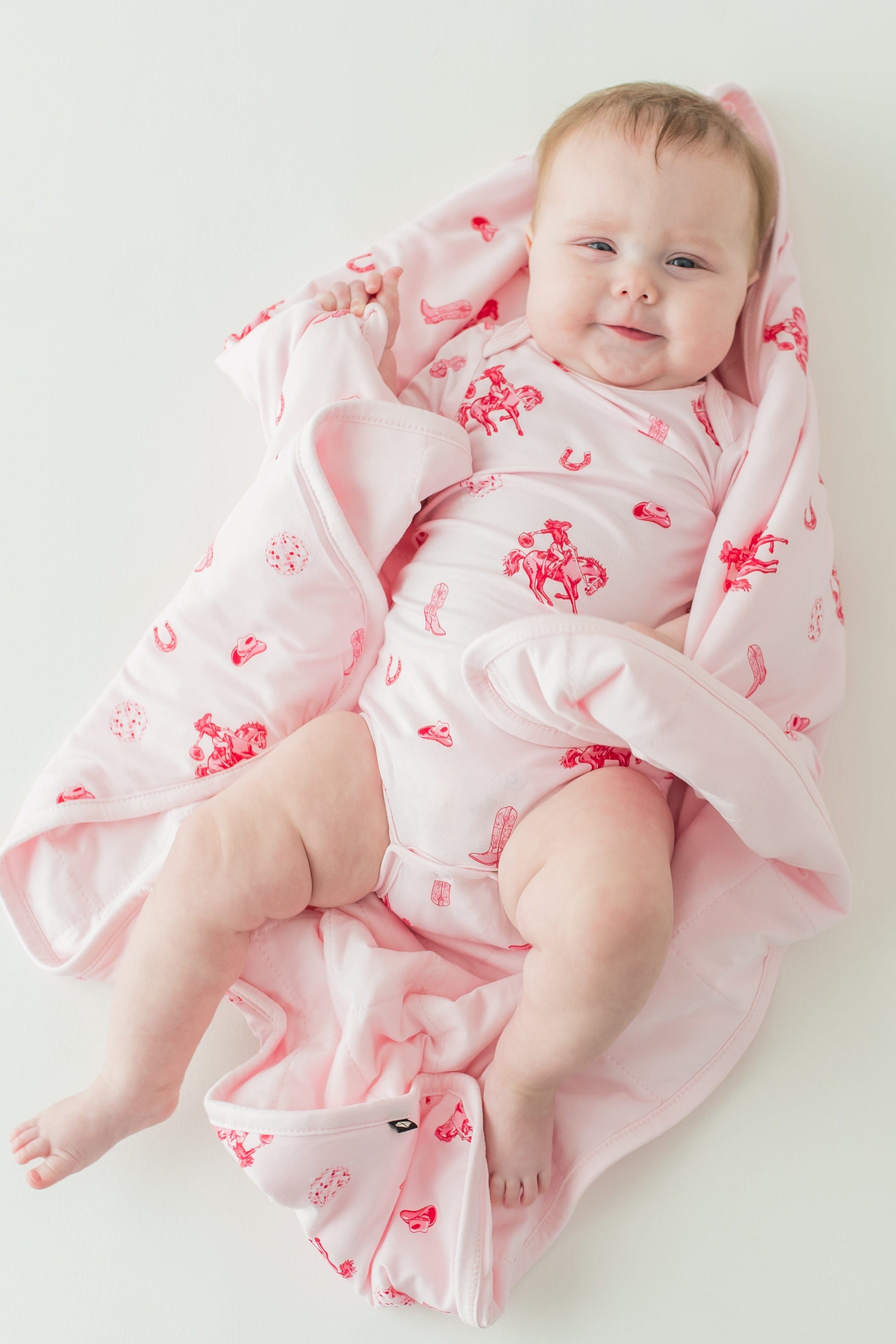 Infant laying on a Baby Blanket in Disco Cowgirl wearing a matching short sleeve bodysuit